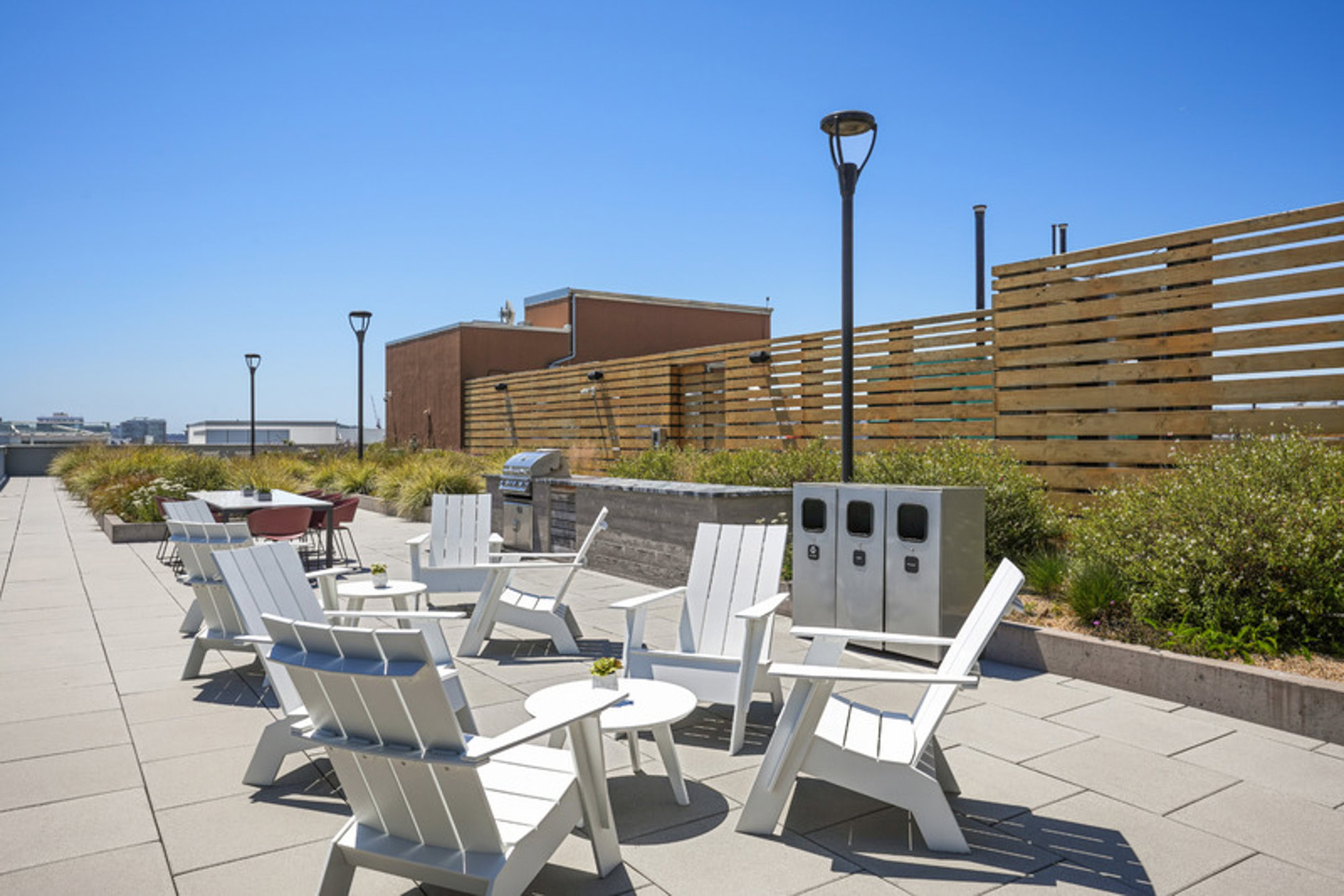 The terrace rooftop with several lounging chairs, outdoor trash cans, and a garden at the Mosso apartments in San Francisco