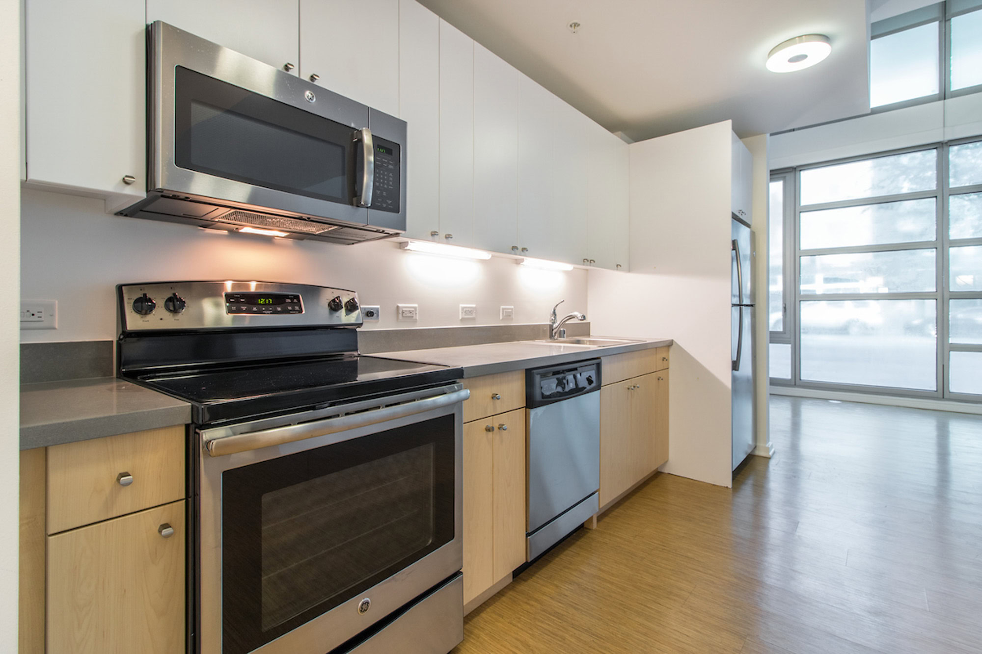 A kitchen in an open plan apartment with large windows in a Mosso apartment in San Francisco