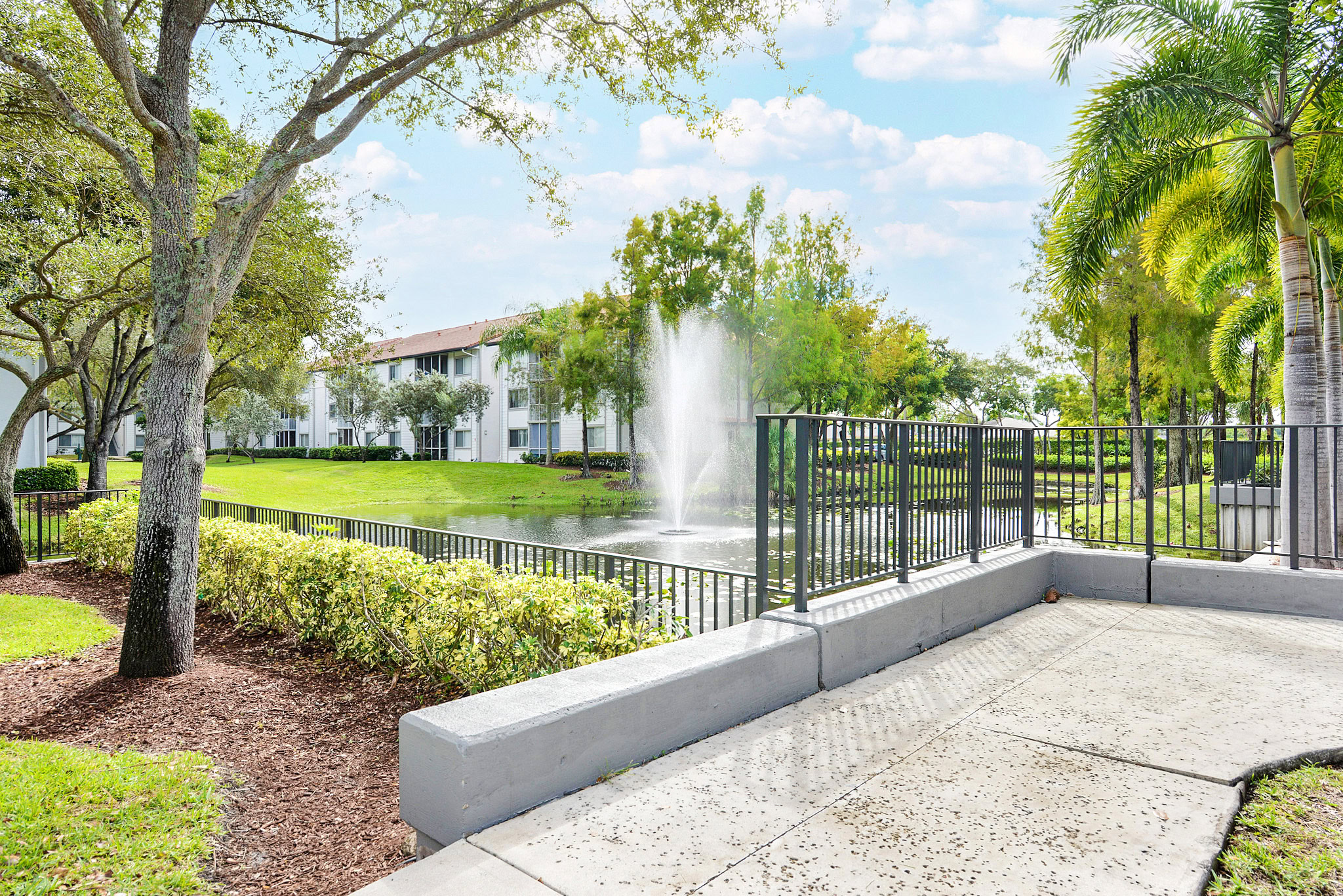 A walking path next to a water feature in a courtyard at Sabal Pointe apartments in South Florida
