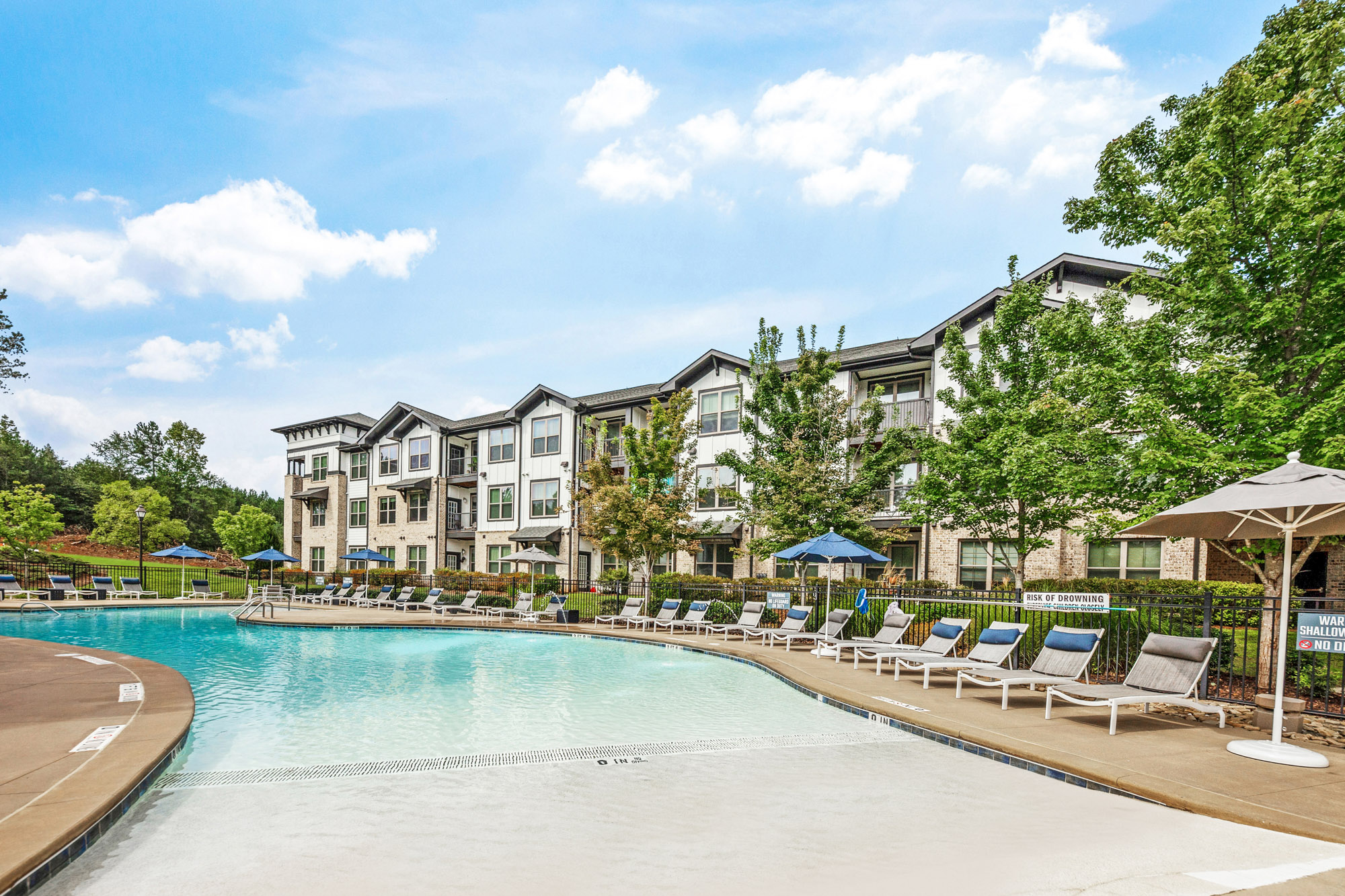 A beach entry swimming pool is surrounded by lounge chairs at Park 9 apartments near Atlanta.