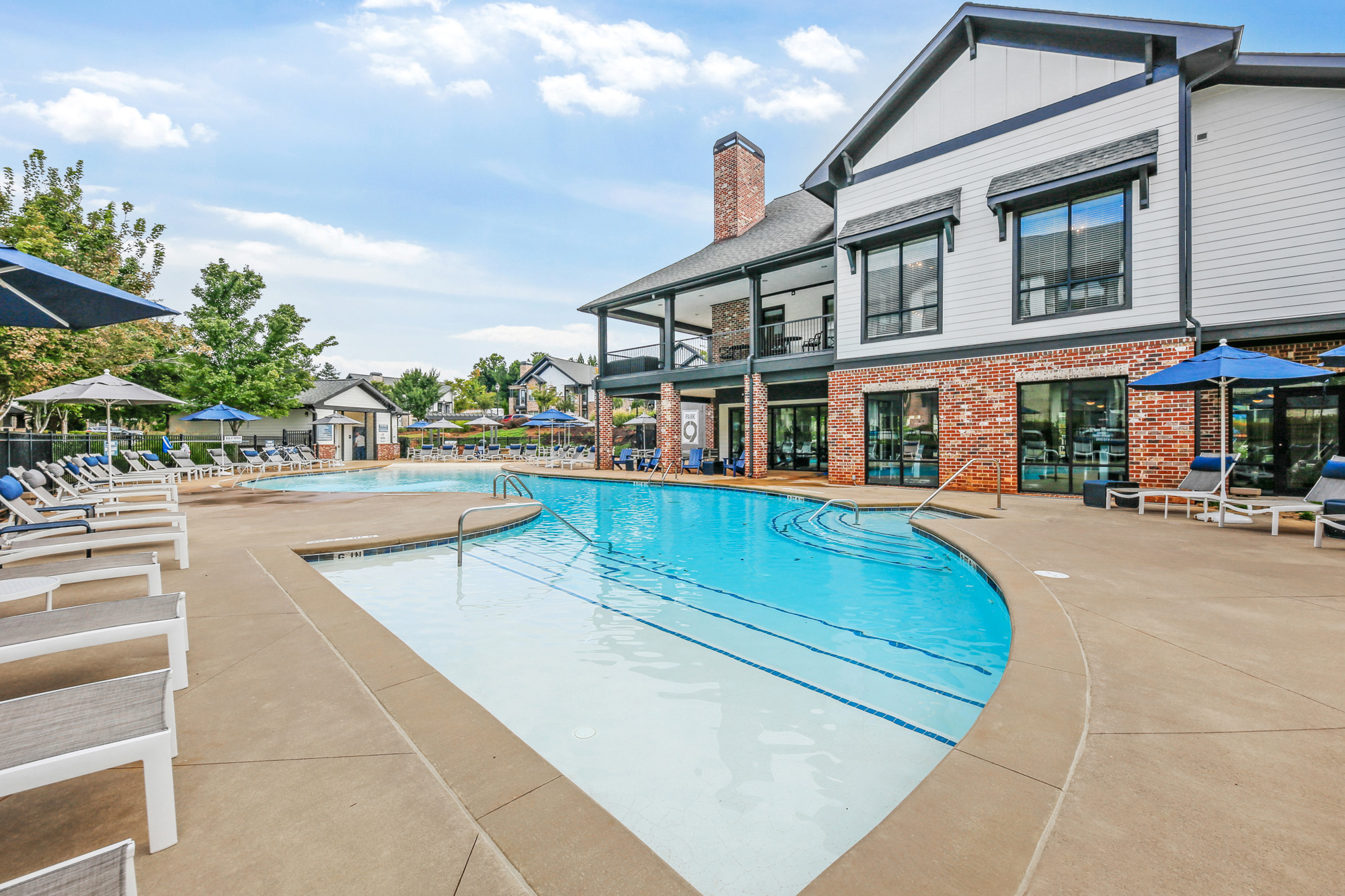 A swimming pool surrounded by lounge chairs with the Park 9 clubhouse in the background.