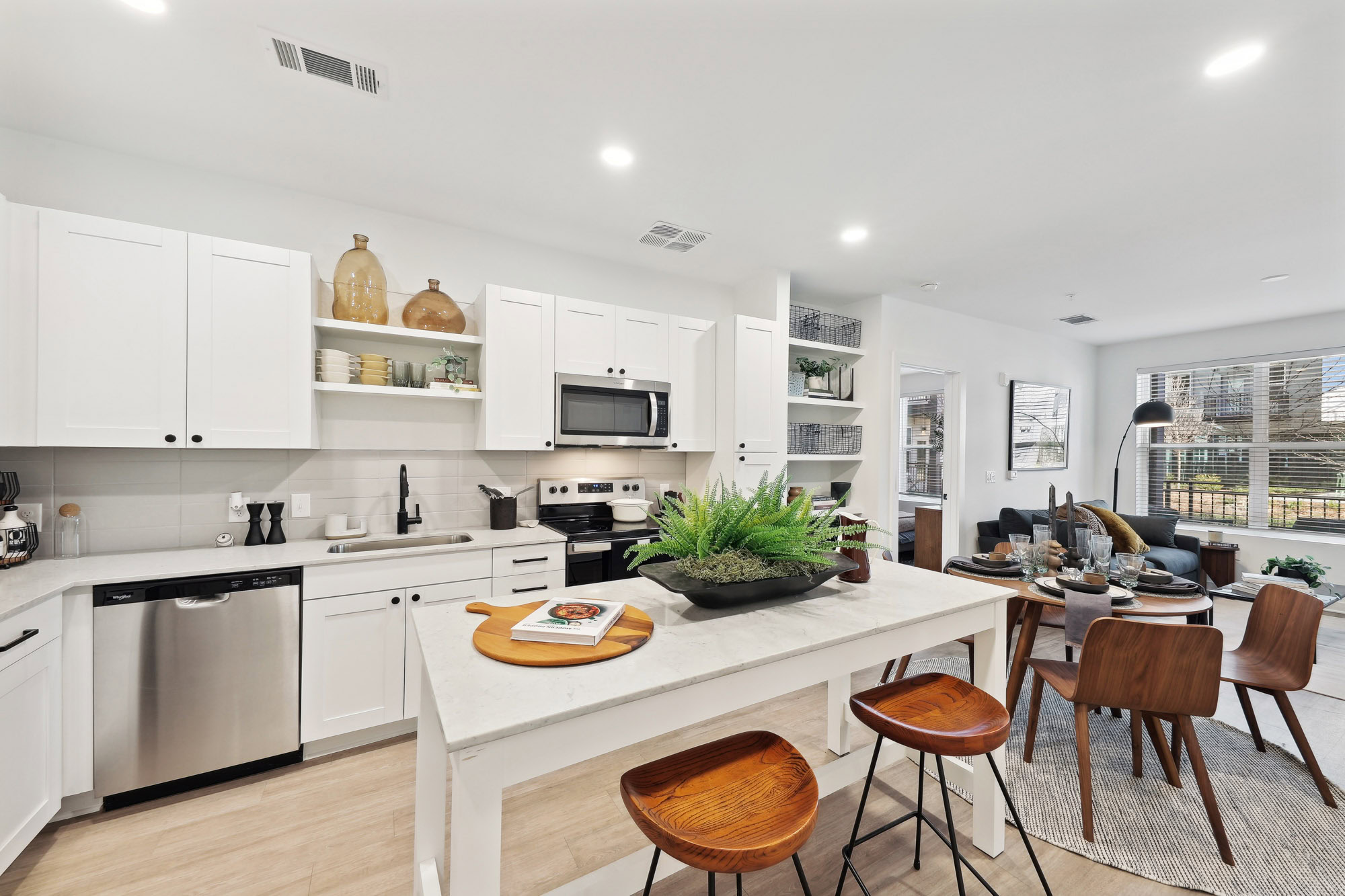 A kitchen with a kitchen island next to a dining area in a Tallulah apartment in Cumberland, GA