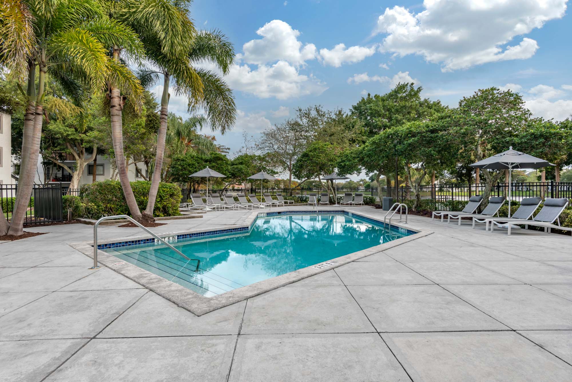 The pool and patio with lounging chairs and umbrellas at The Reserve at Ashley Lake apartments