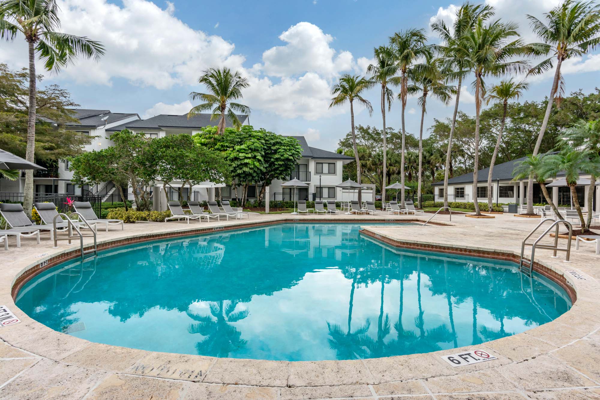 The pool and patio with lounging chairs and umbrellas at The Reserve at Ashley Lake apartments