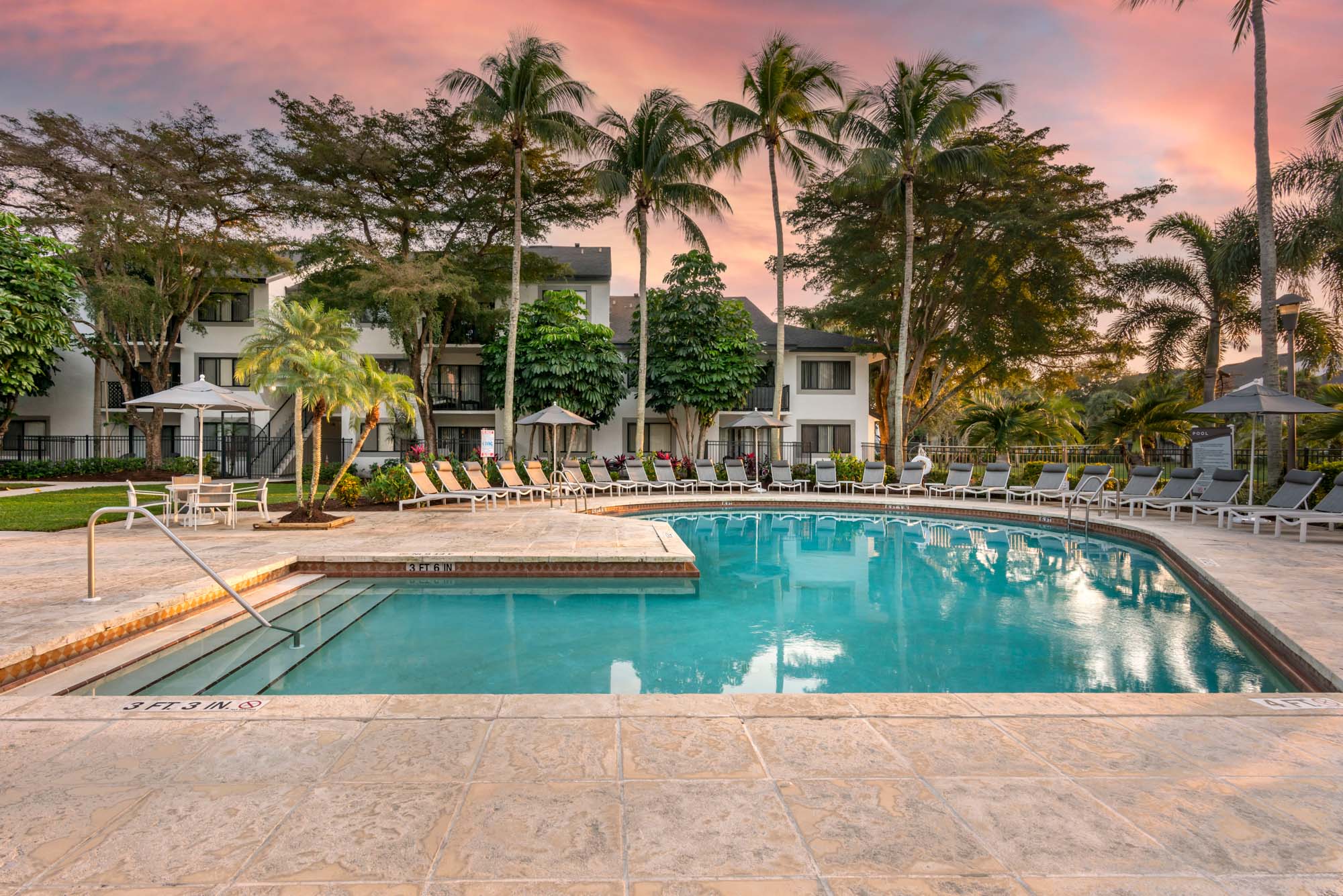 The pool and patio with lounging chairs and umbrellas at The Reserve at Ashley Lake apartments