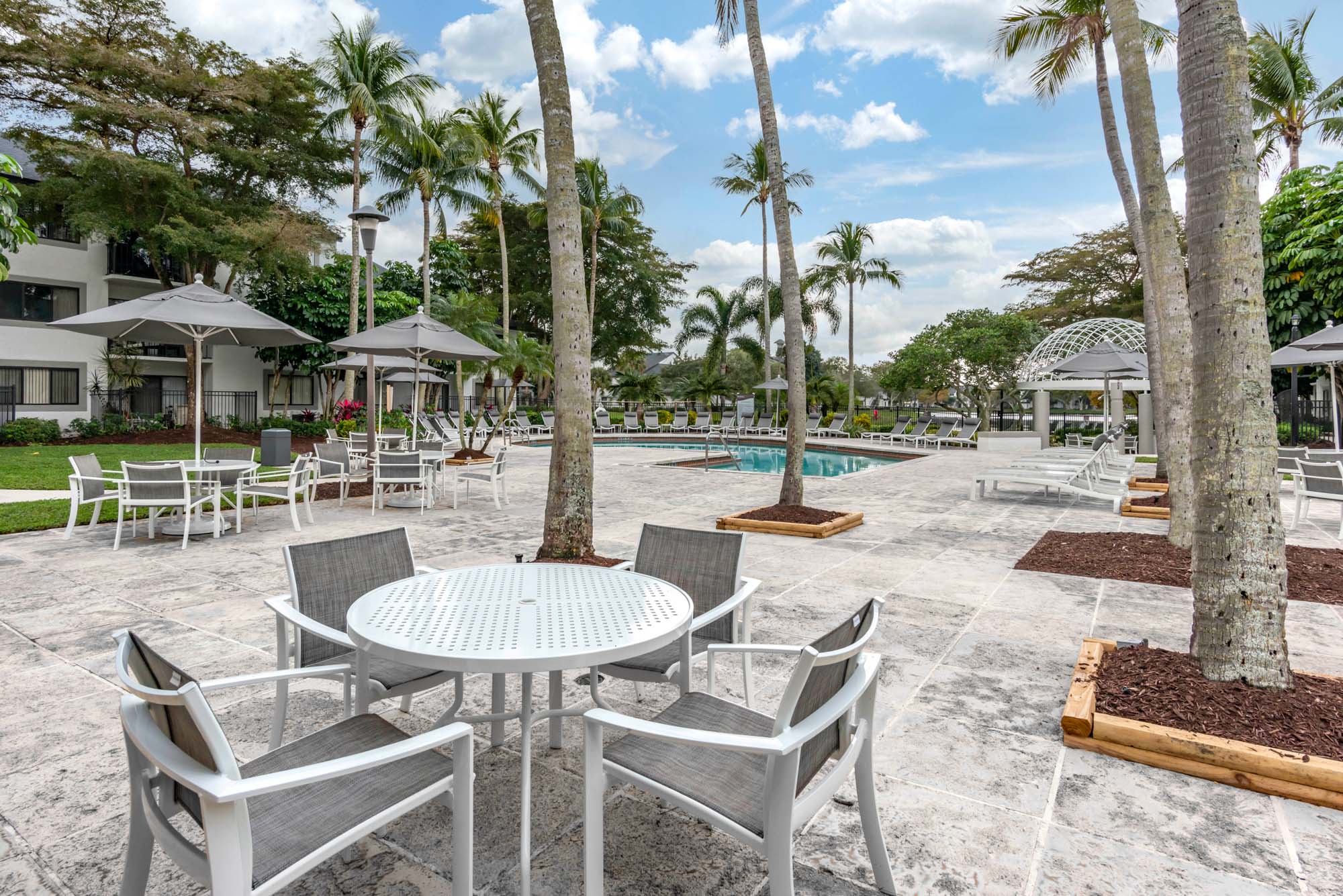 The pool patio with outdoor dining tables and umbrellas at The Reserve at Ashley Lake apartments