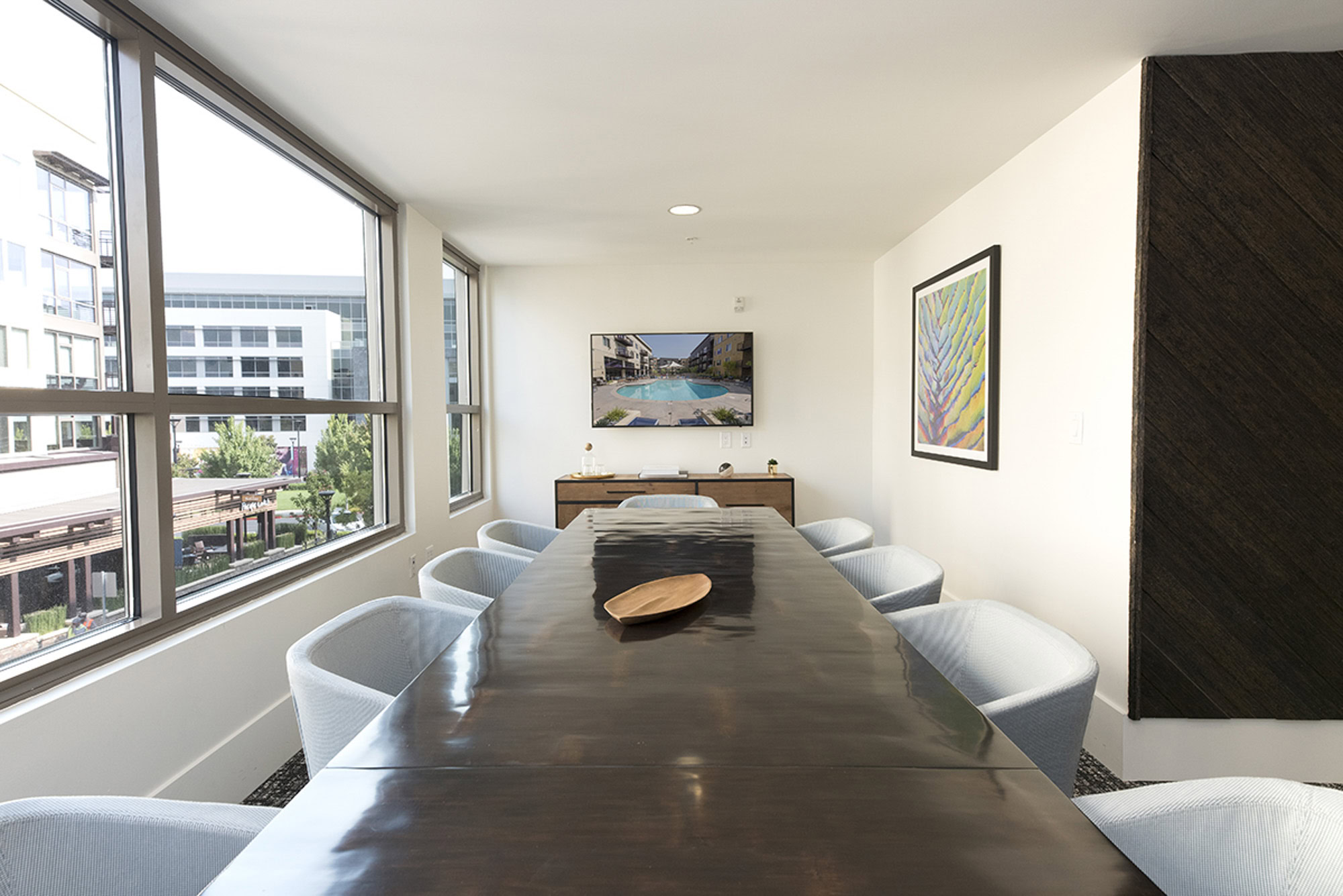 A conference room with a long conference table and large windows with courtyard views at The Village Residences in Mountain View, CA