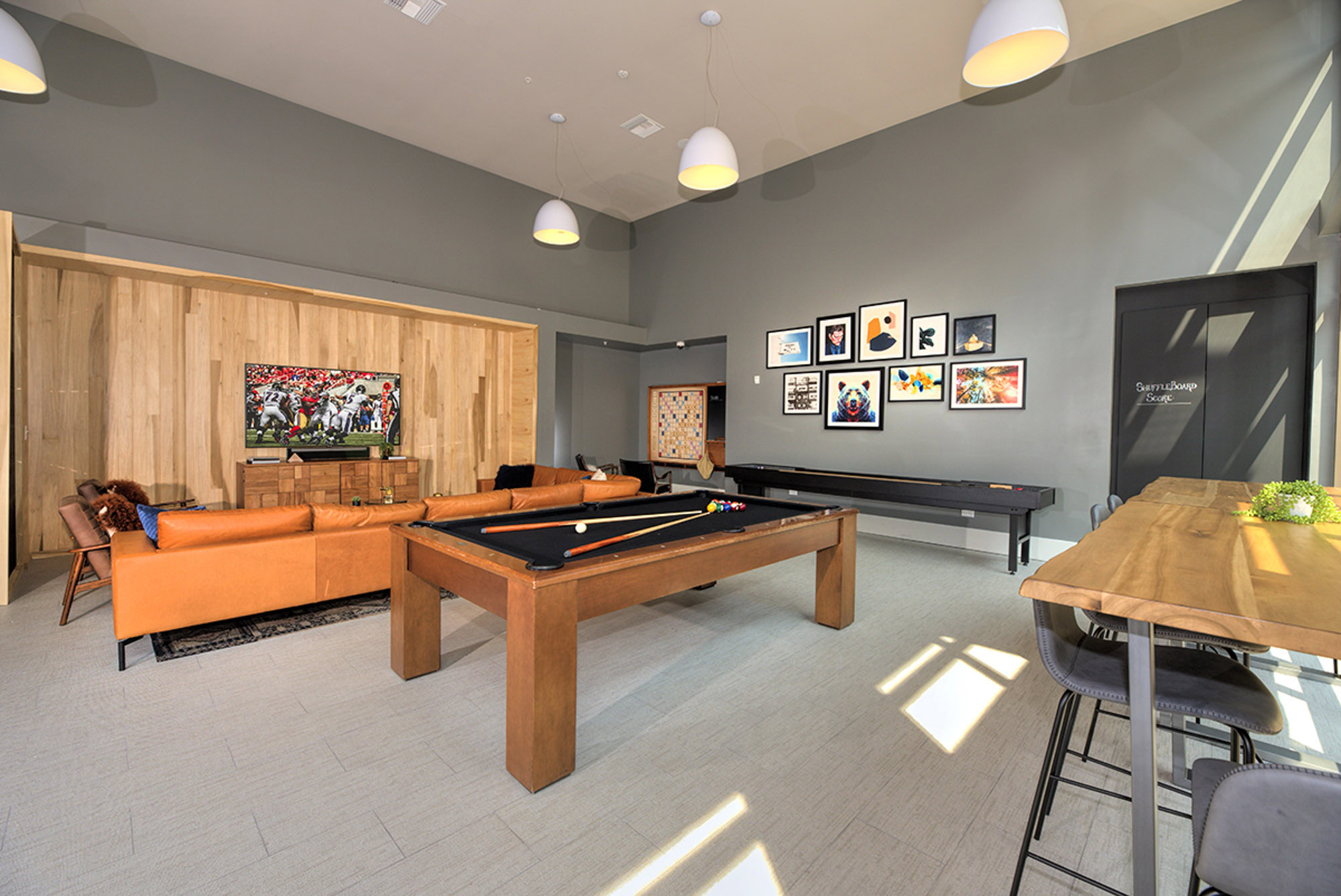 A game room featuring a pool table, shuffleboard, leather couches and a TV at The Village Residences Mountain View, CA luxury apartments