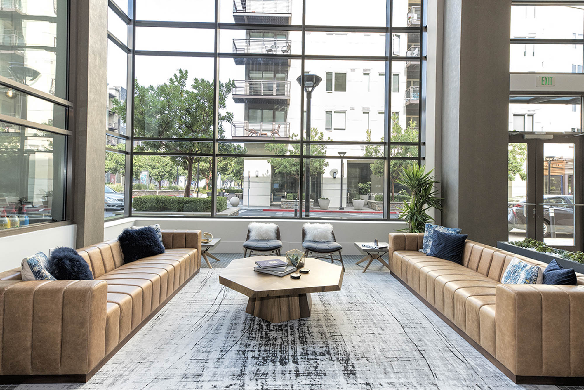 A lobby lounge with leather couches and large glass windows with street level views at The Village Residences in Mountain View
