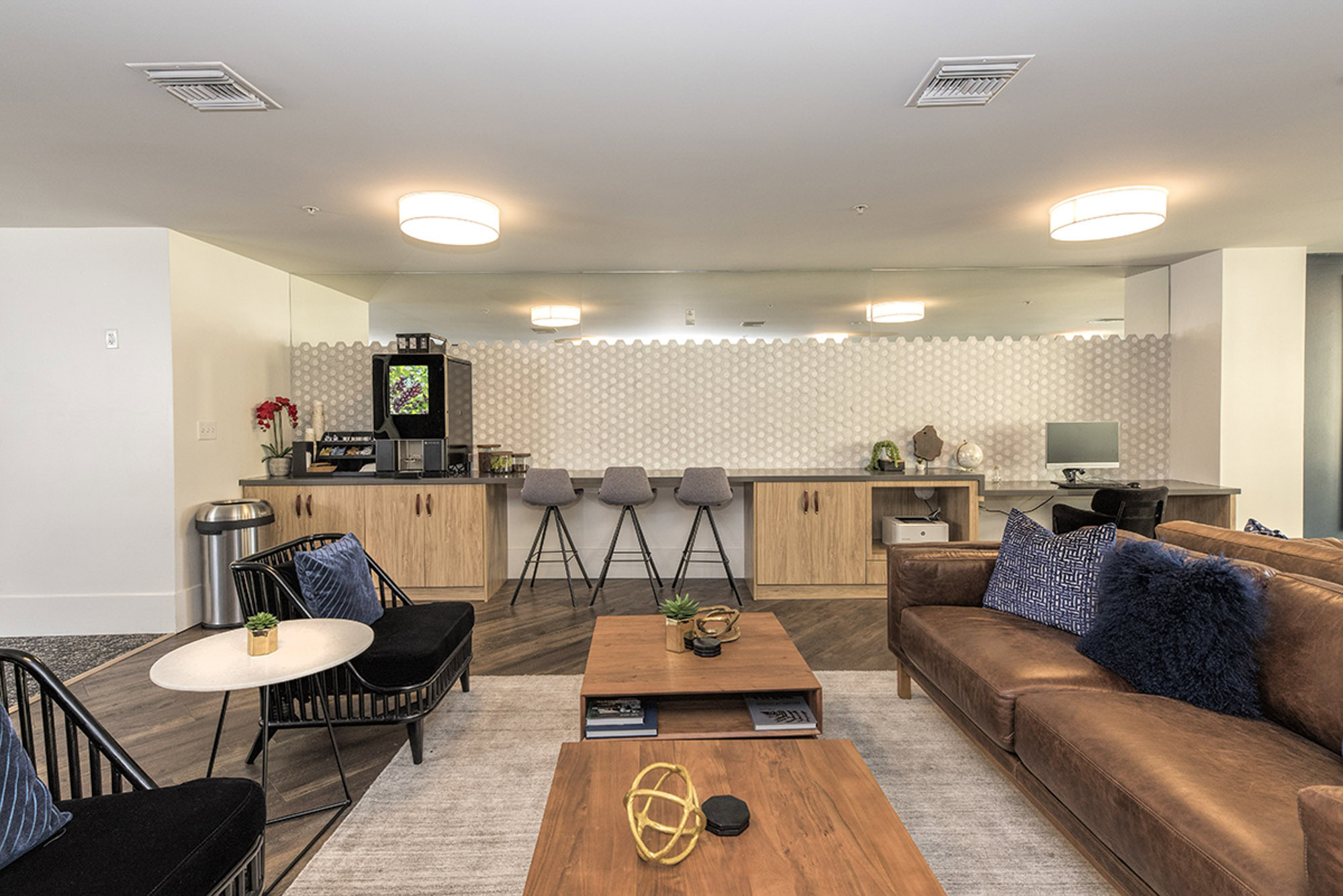 A lounge with a computer station, coffee and tea station and seating area at The Village Residences new apartments in Mountain View