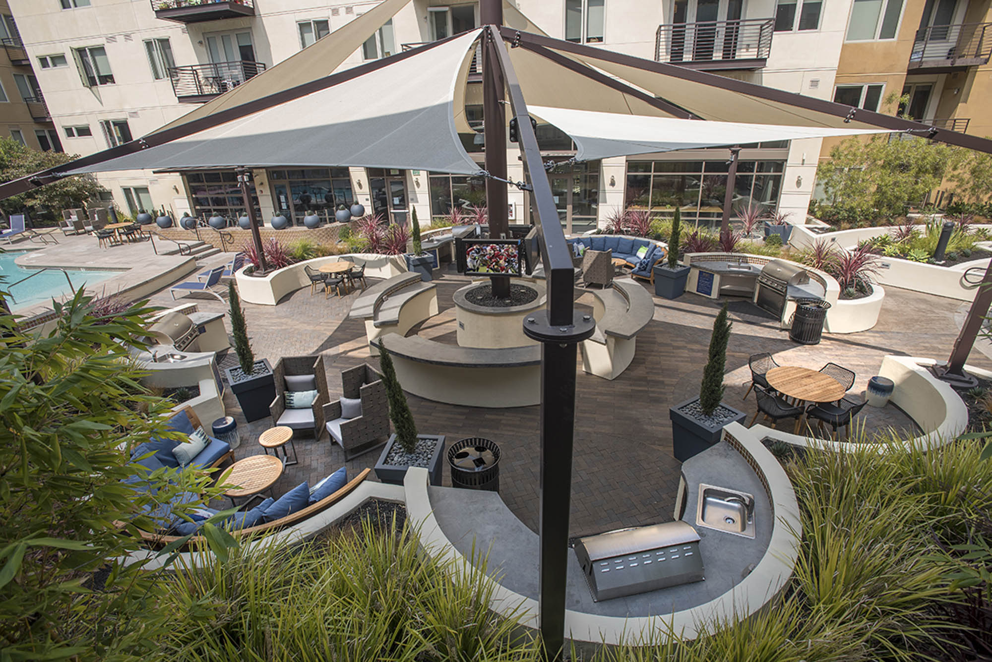 The pool courtyard entertainment area featuring grilling stations and lounge seating at The Village Residences new apartments in Mountain View, CA