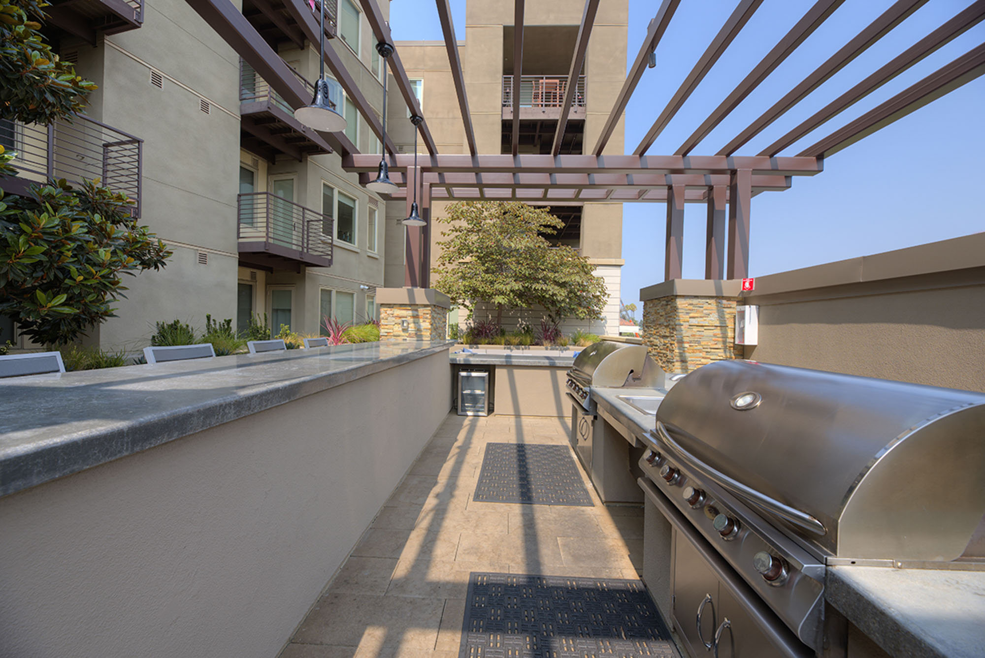An enclosed grilling station with two grills, a mini fridge and high seating for entertainment at The Village Residences Mountain View apartments