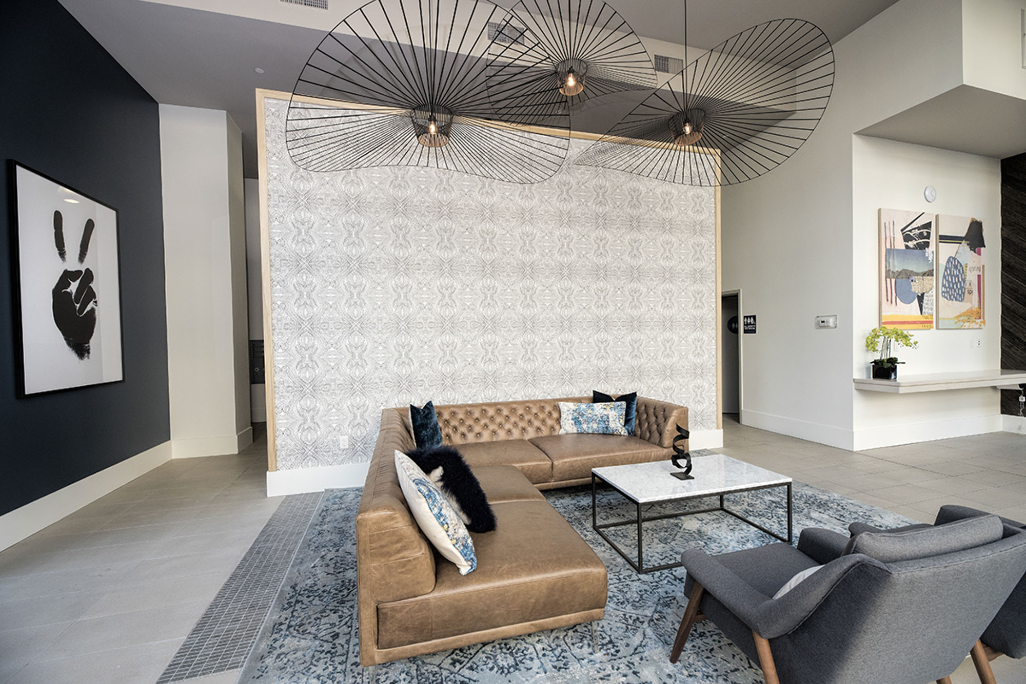 A small lounge with a leather L shaped couch and a partition wall covering the restrooms in the lobby of The Village Residences new apartments in Mountain View, CA