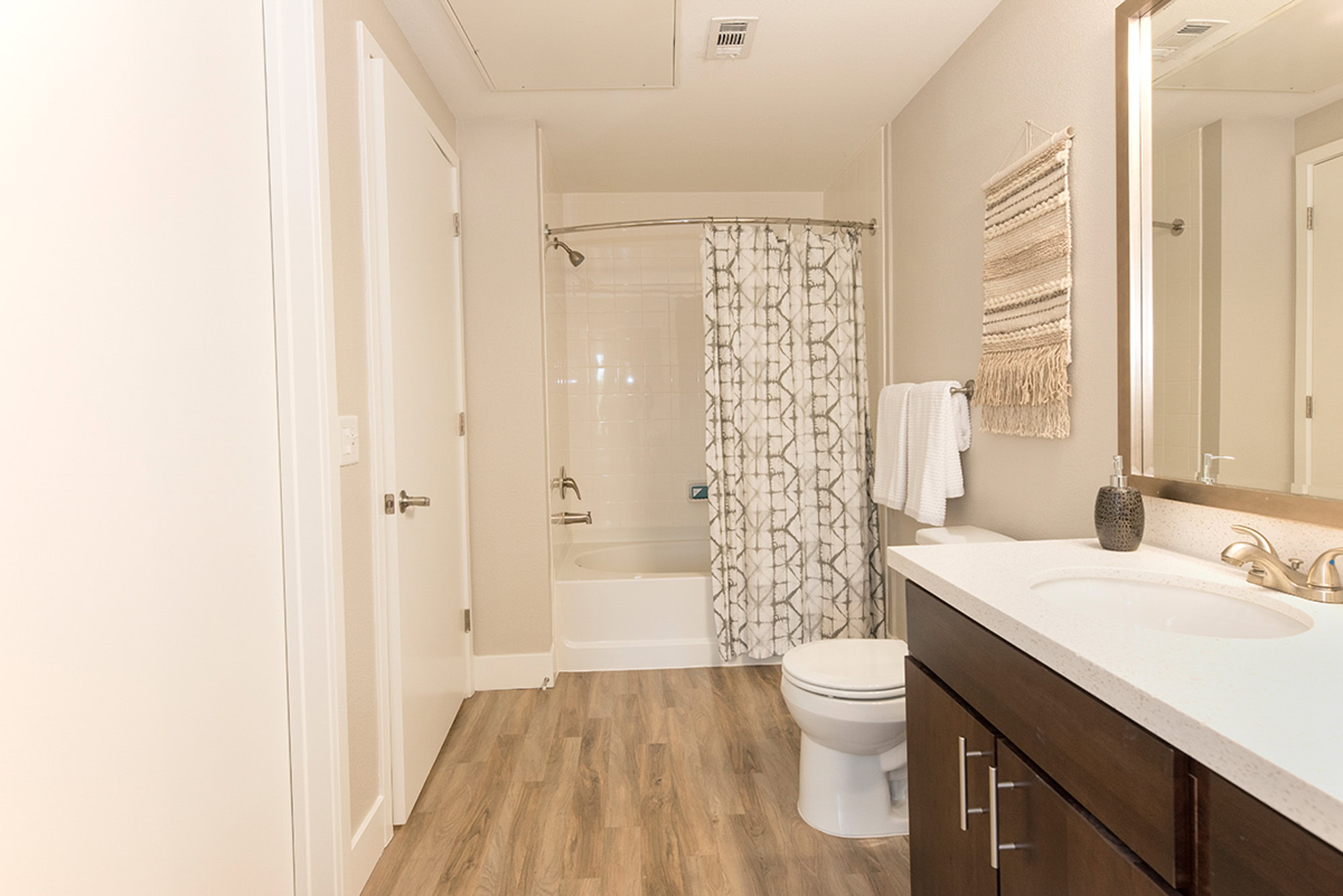 A bathroom with a tub and shower combo and hardwood floors at The Village Residences new apartments in Mountain View, CA