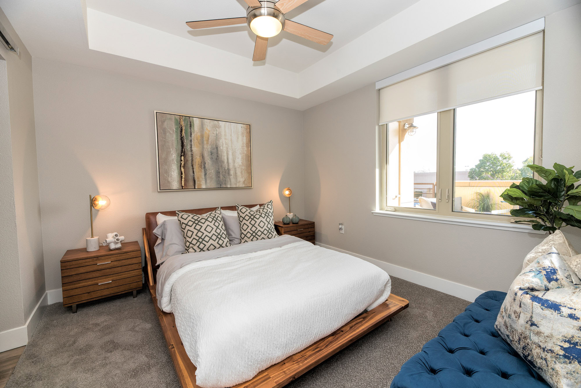 A carpeted bedroom with a large window in The Village Residences apartments in Mountain View, CA