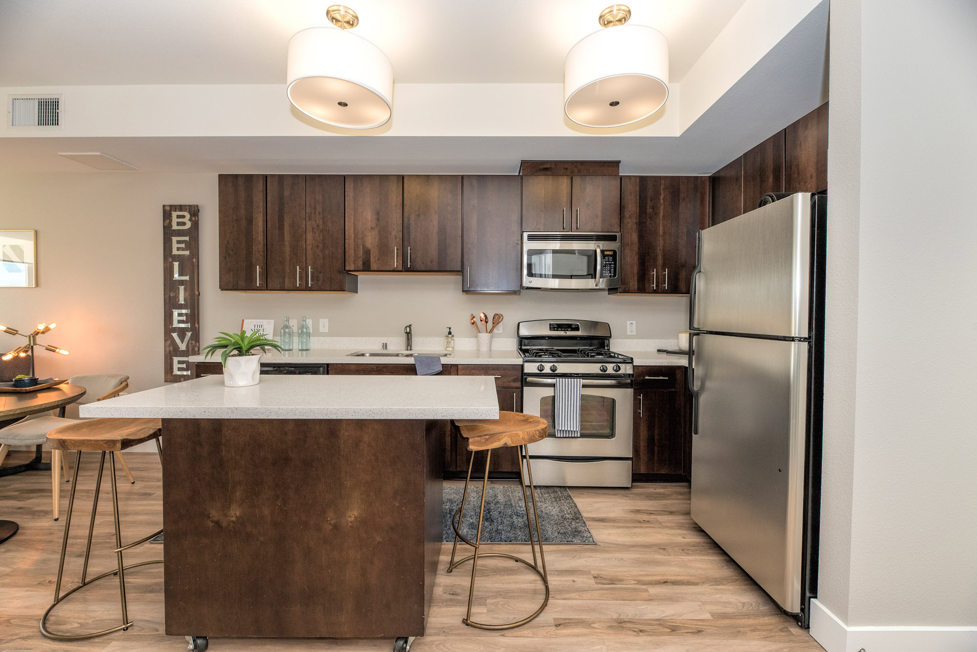 A kitchen with hardwood floors, brown cabinets and a movable kitchen island at The Village Residences new apartments in Mountain View, CA