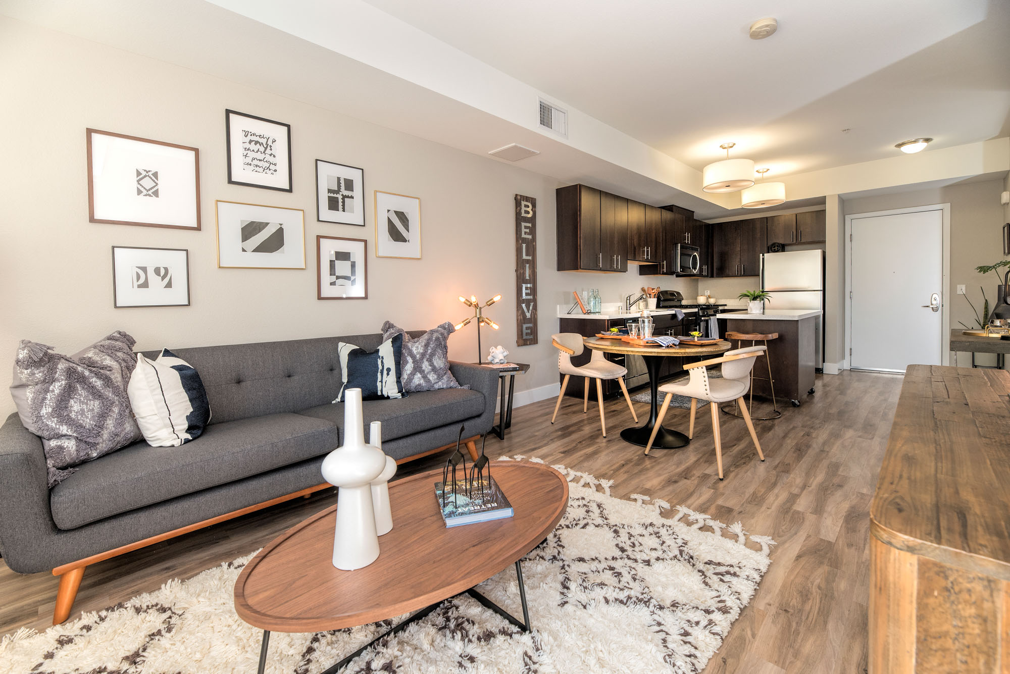 An open plan living room with a dining space and kitchen with a movable island at The Village Residences new apartments in Mountain View, CA