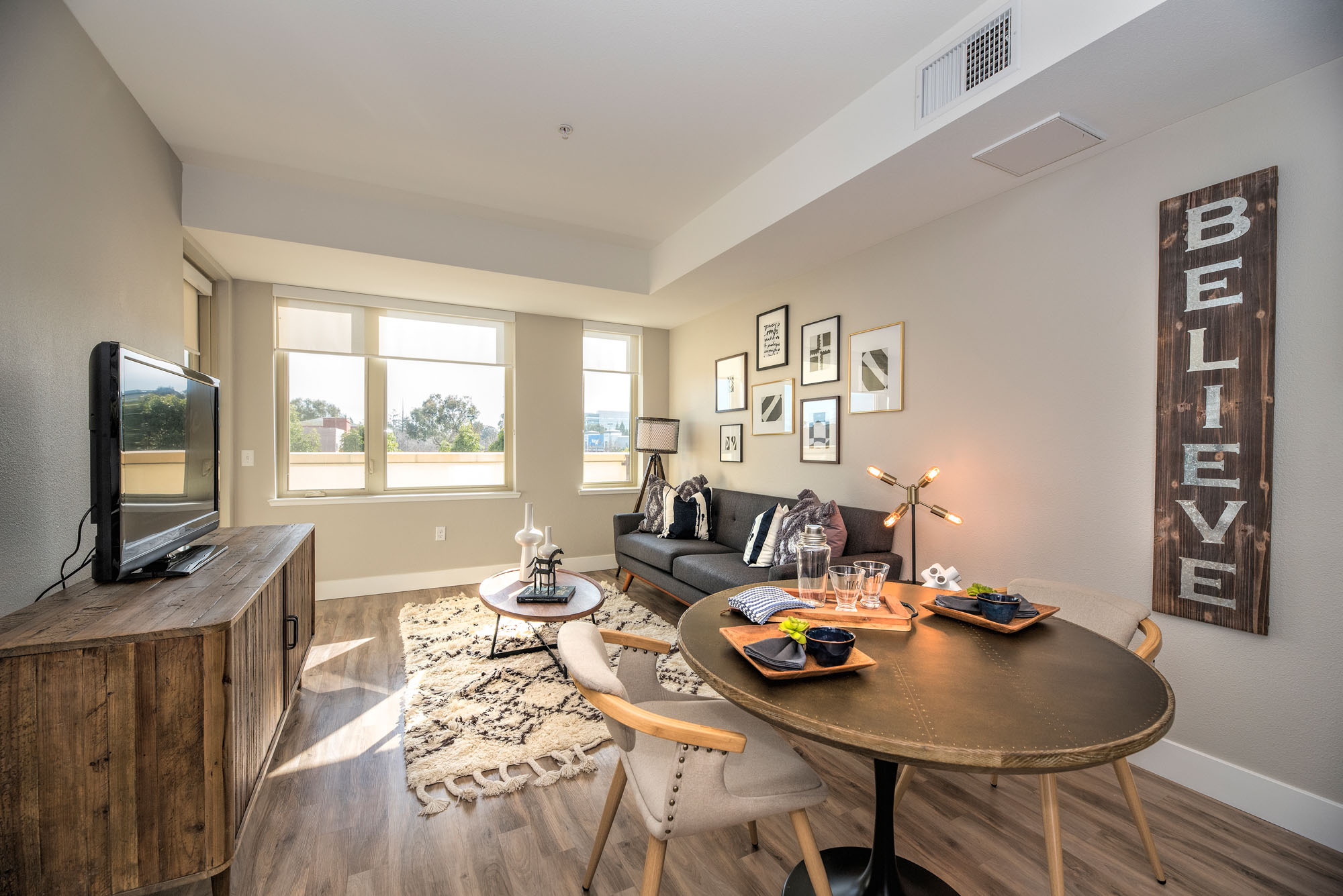 A dining area and living room with three windows at The Village Residences new apartments in Mountain View, CA