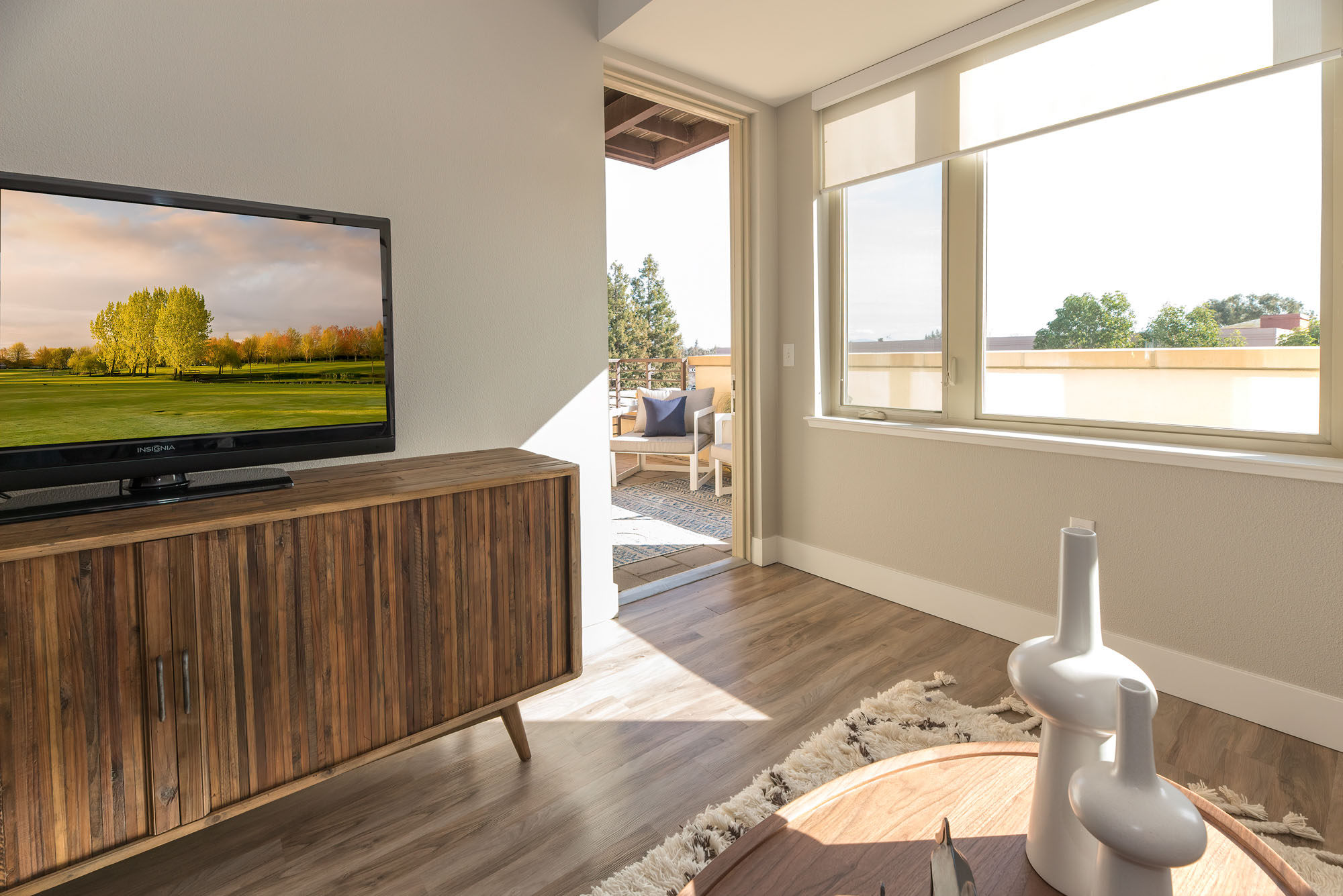 A living room with a large window next a door leading to a balcony in an apartment at the Village of Residences in Mountain View, CA