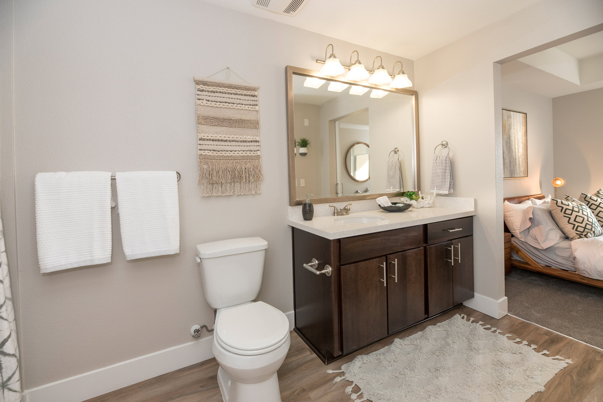 A bathroom with a spacious sink counter and hardwood floors next to a carpeted bedroom at The Village Residences luxury apartments in Mountain View, CA
