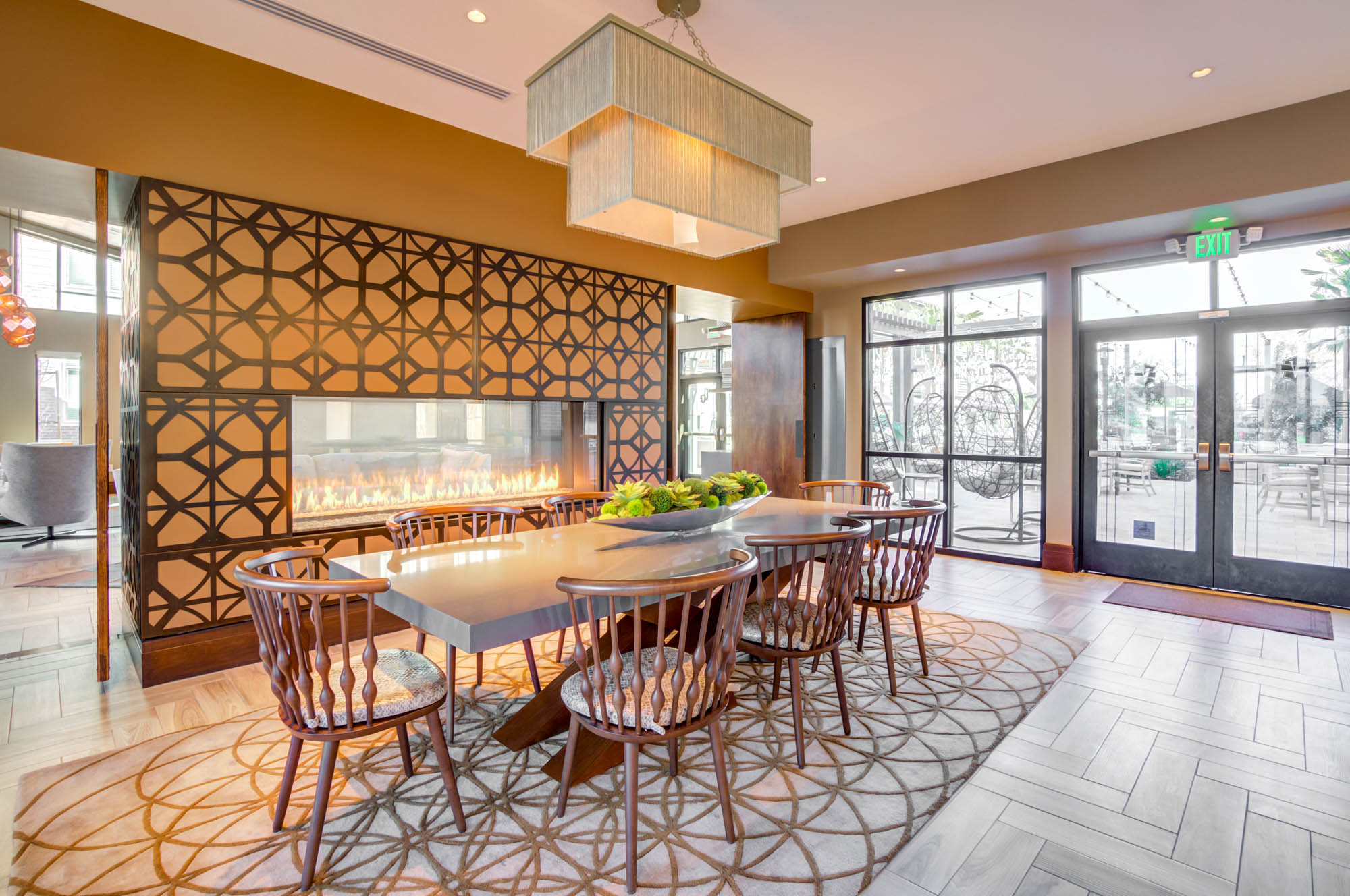 A dining table next to a modern mounted fireplace at the Vintage apartments in Pleasanton, CA