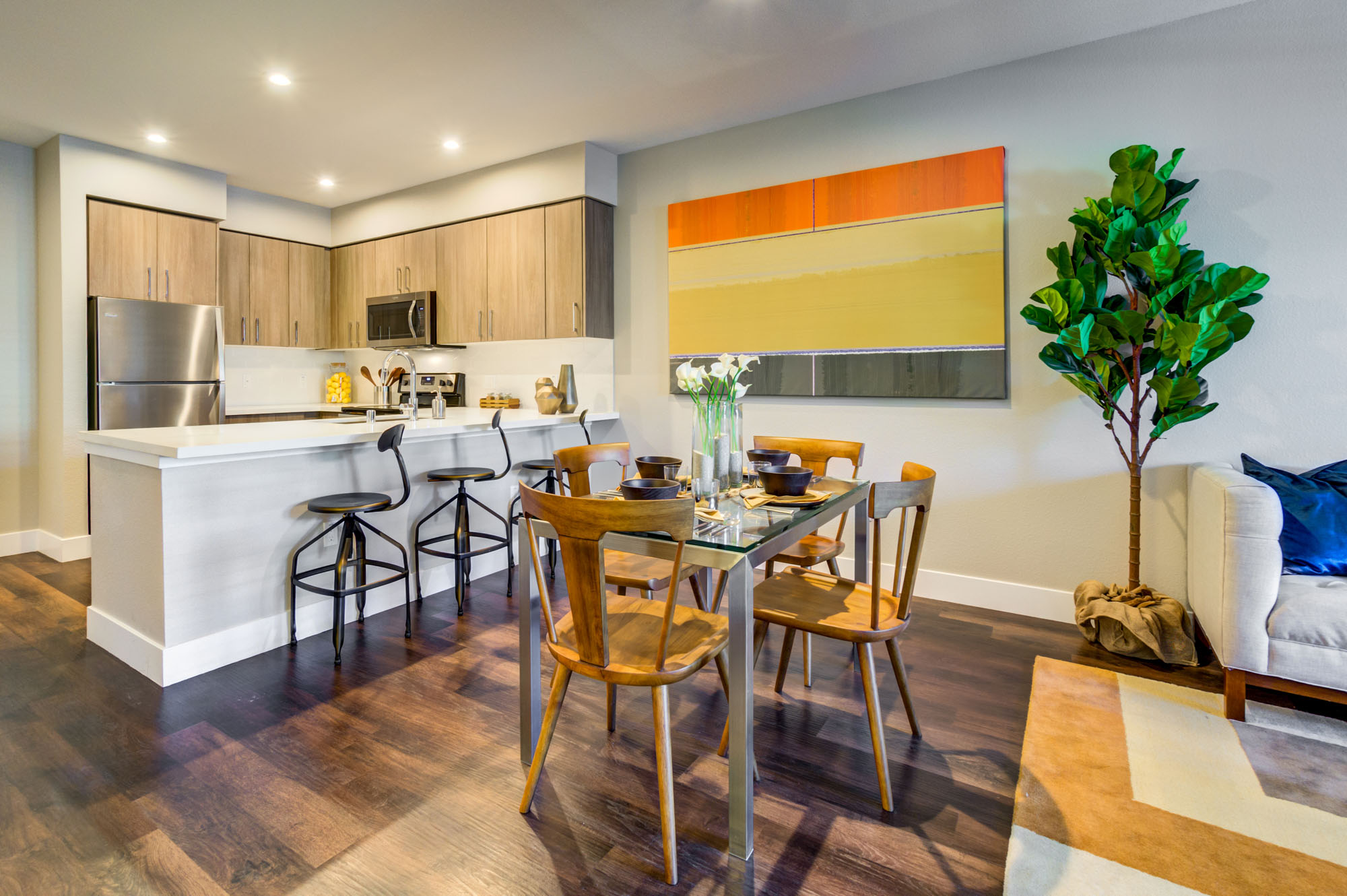 A dining room area in front of a kitchen peninsula and dining table at the Vintage apartments in Pleasanton, CA