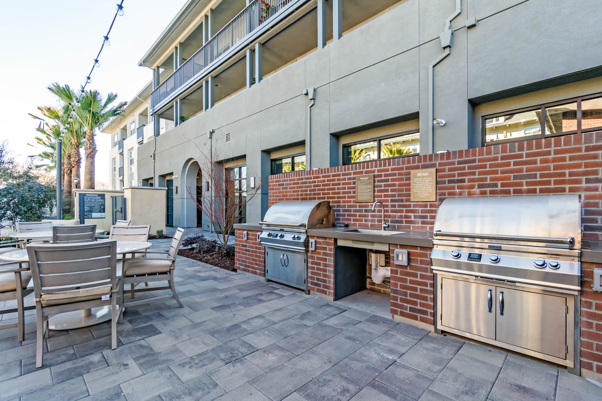 An outdoor grilling stations with dining tables at the Vintage apartments in Pleasanton, CA