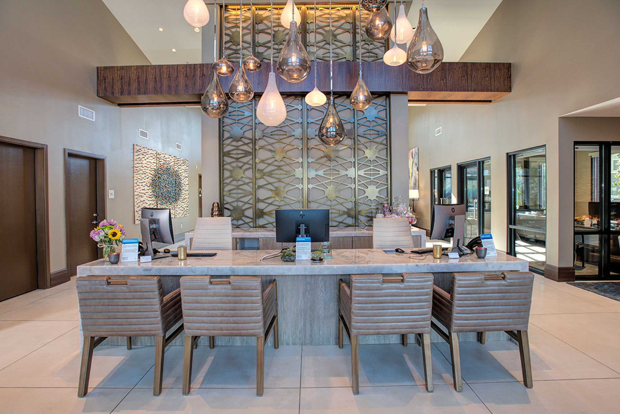 A lobby front desk with four chairs in a modern lobby at the Vintage luxury apartments in Pleasanton, CA