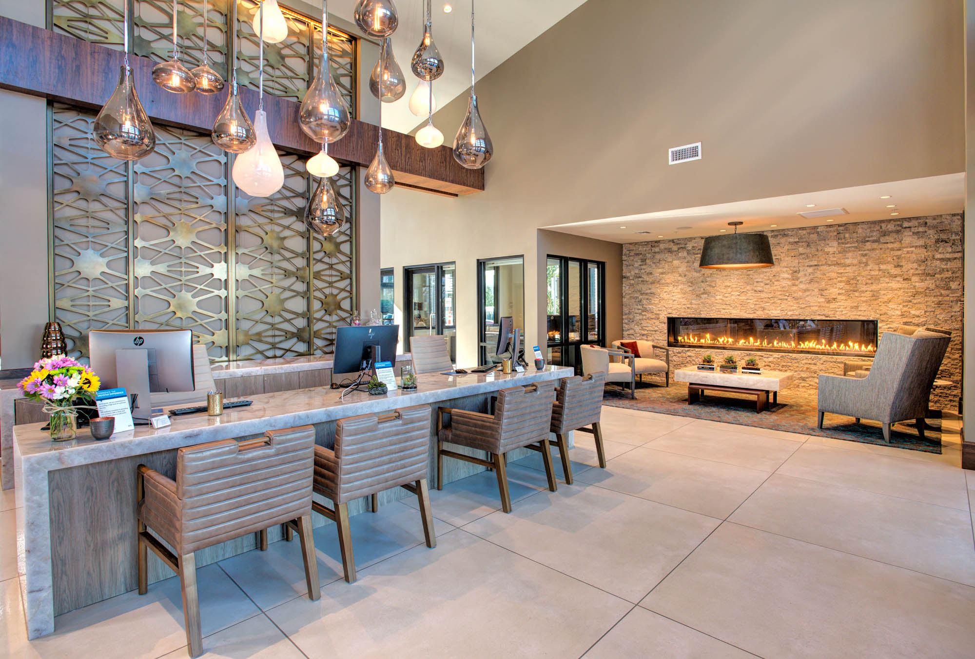 A lobby front desk next to a lounge with a fireplace at the Vintage luxury apartments in Pleasanton, CA