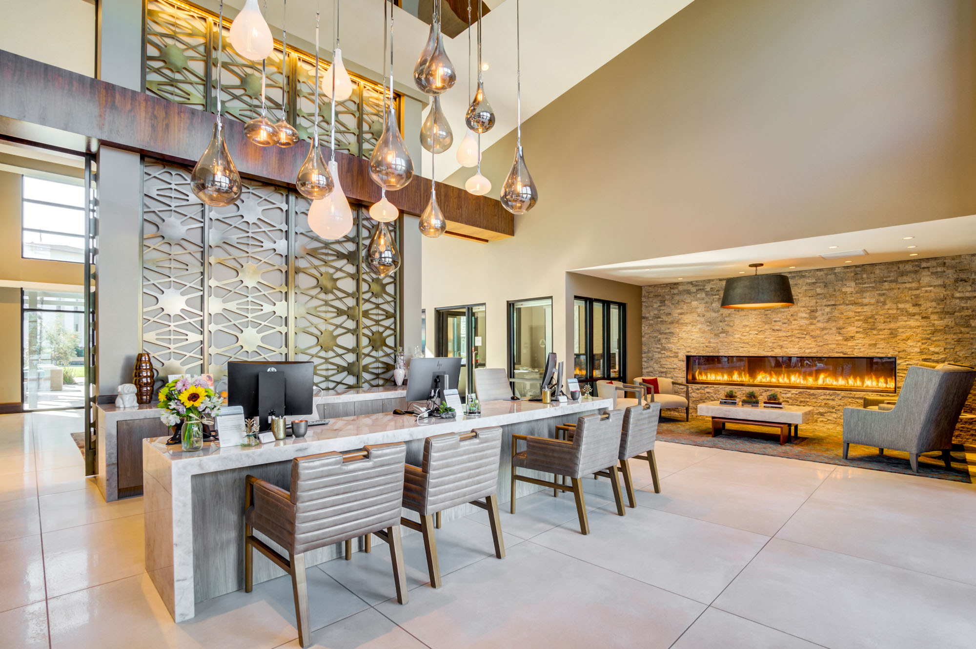 A lobby front desk next to a lounge with a fireplace at the Vintage luxury apartments in Pleasanton, CA