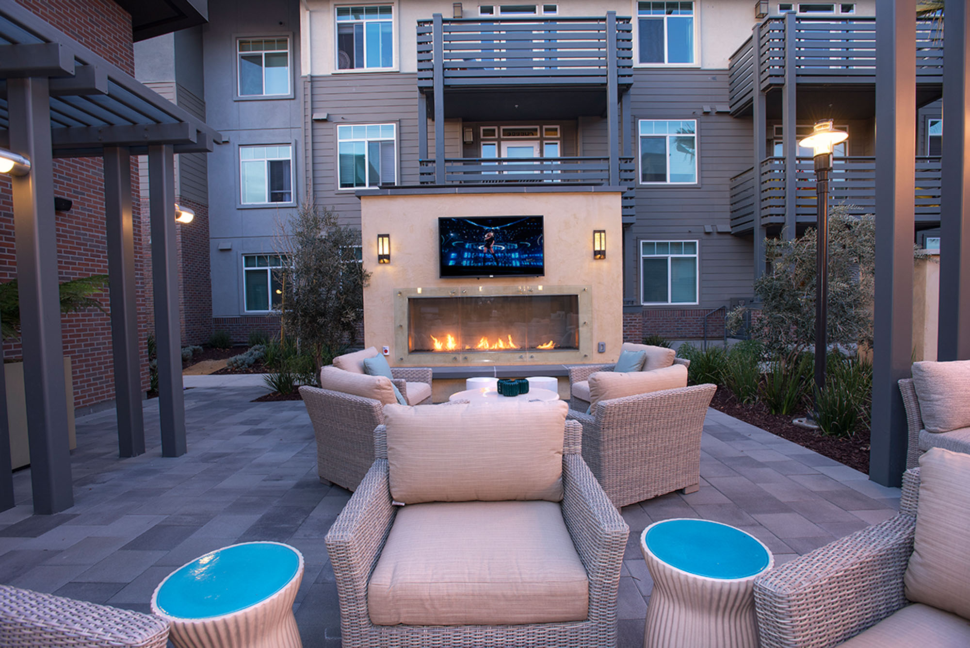 An outdoor terrace with several seating areas and a fireplace at Vintage apartments in Pleasanton, CA