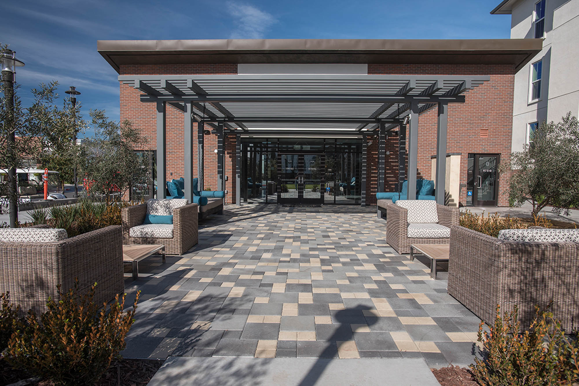An outdoor lounge on a spacious walkway from sliding doors partially covered by a pergola at the Vintage apartments in Pleasanton, CA