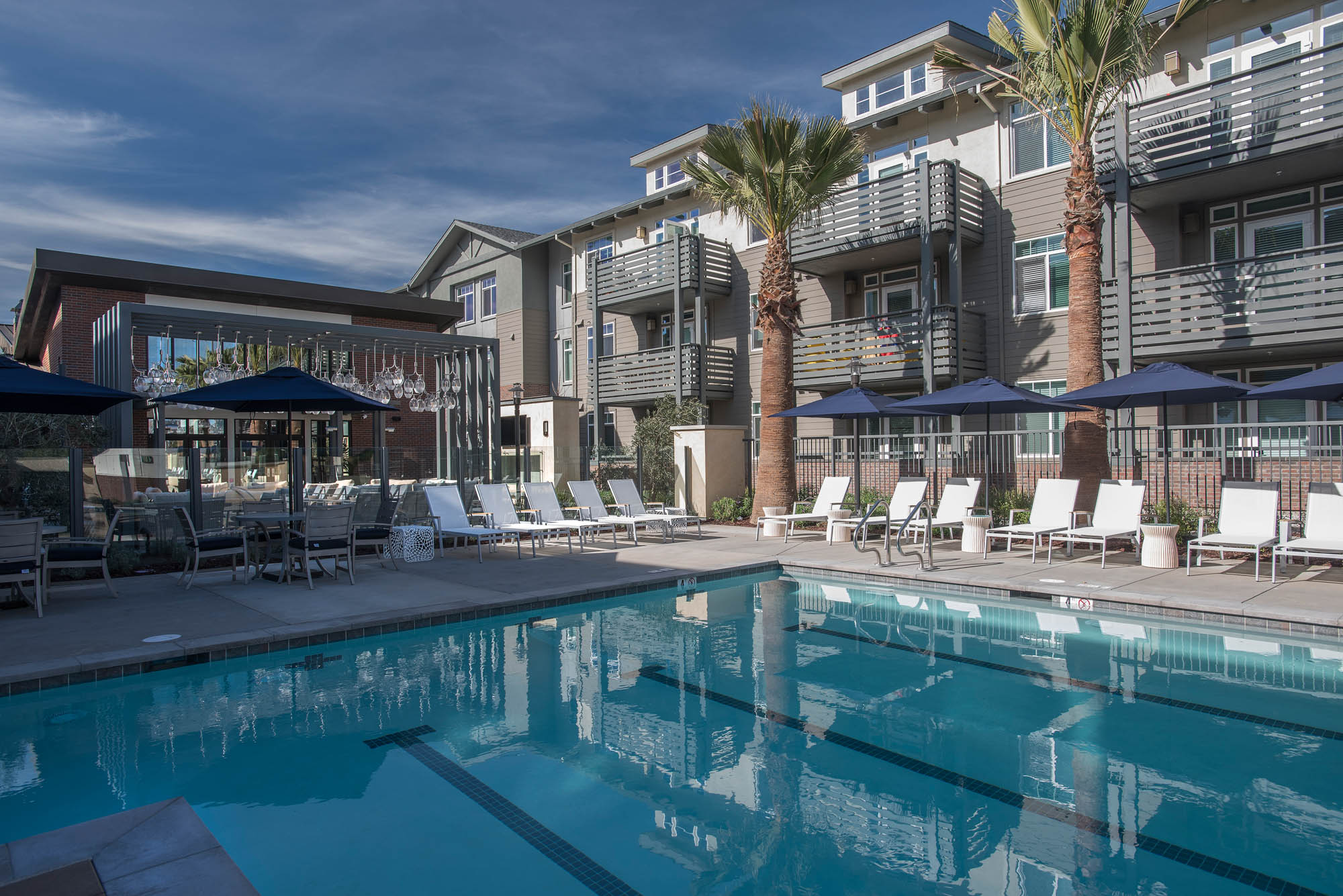 An outdoor pool with lanes surrounding by lounging chairs at Vintage luxury apartments in Pleasanton CA