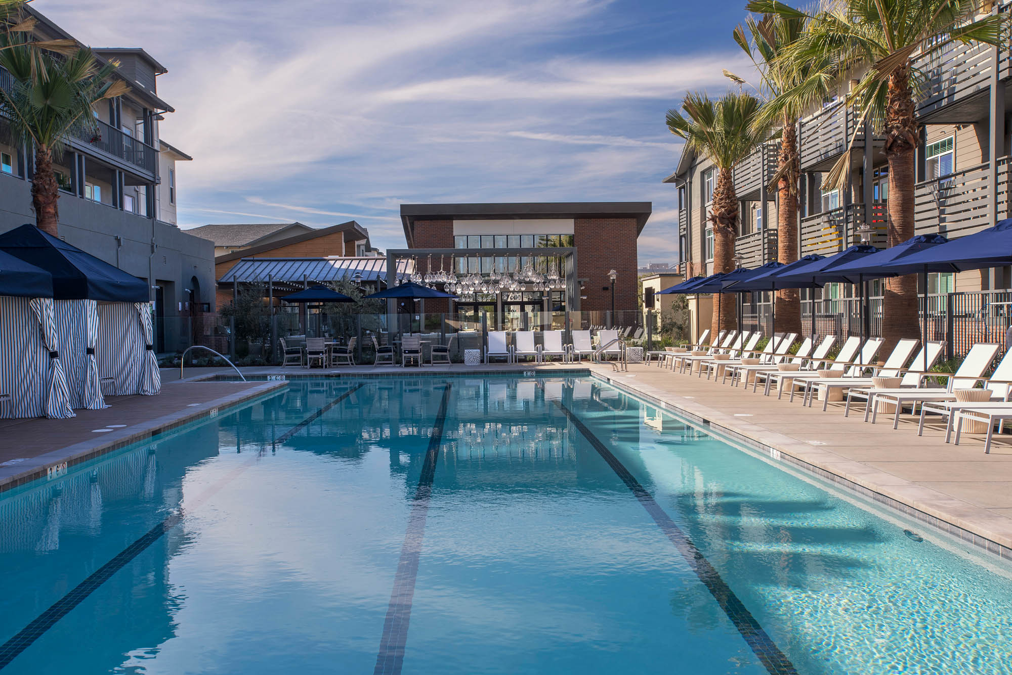 A pool with four lanes, and lounging chairs and cabanas on either side at the Vintage luxury apartments in Pleasanton, CA