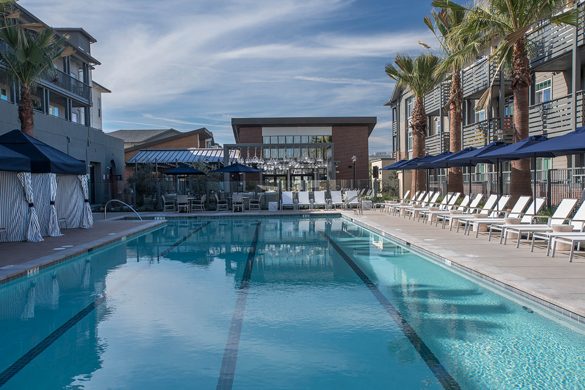 A pool with four lanes, and lounging chairs and cabanas on either side at the Vintage luxury apartments in Pleasanton, CA