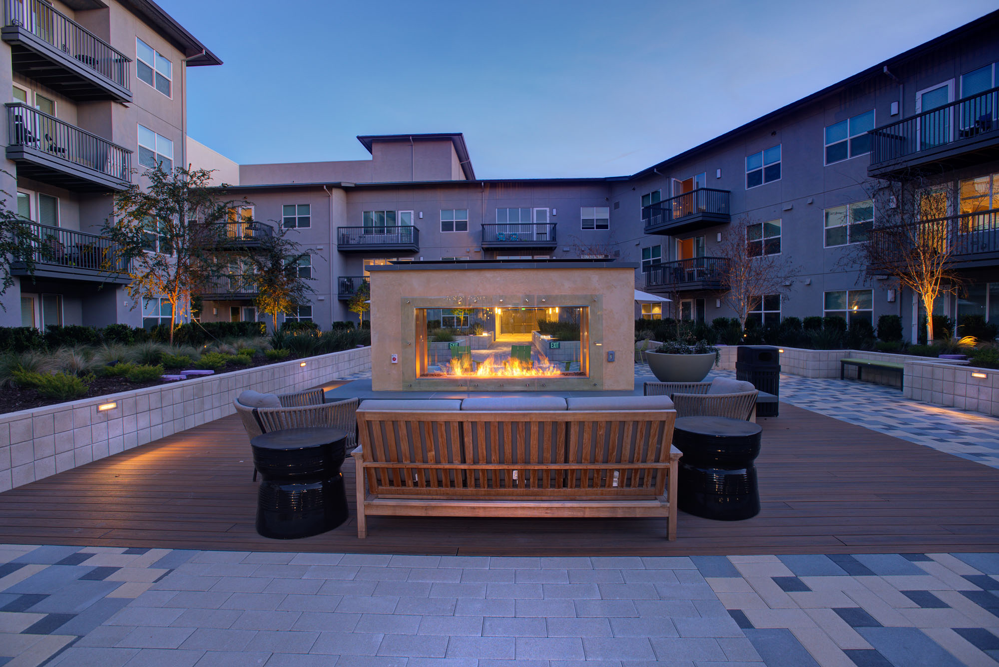 A modern fireplace with lounging chairs on a deck in a courtyard at the Vintage apartments in Pleasanton, CA