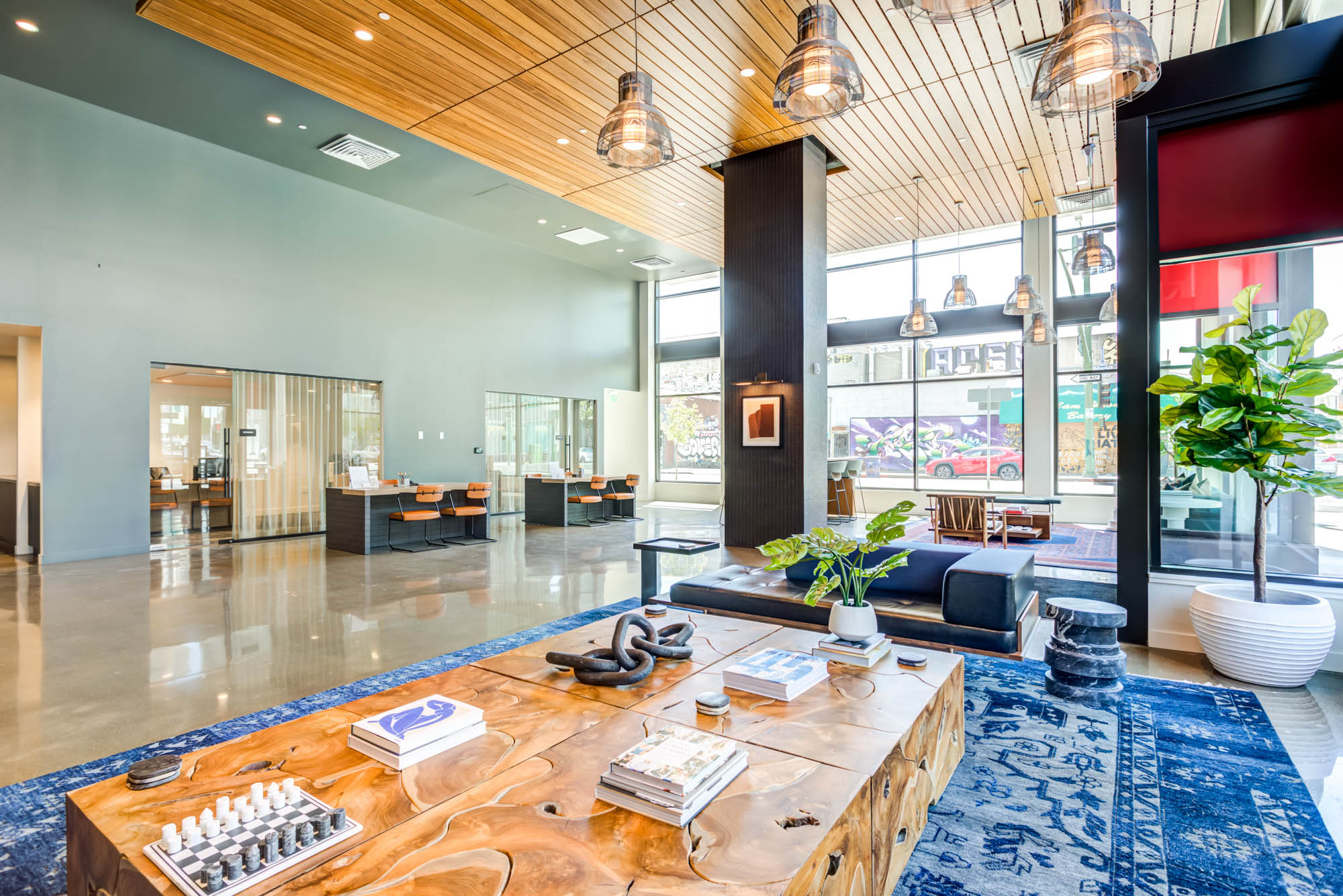 A modern lobby lounge with large wooden coffee tables and. blue persian rug at the Webster Eleven apartments in downtown Oakland