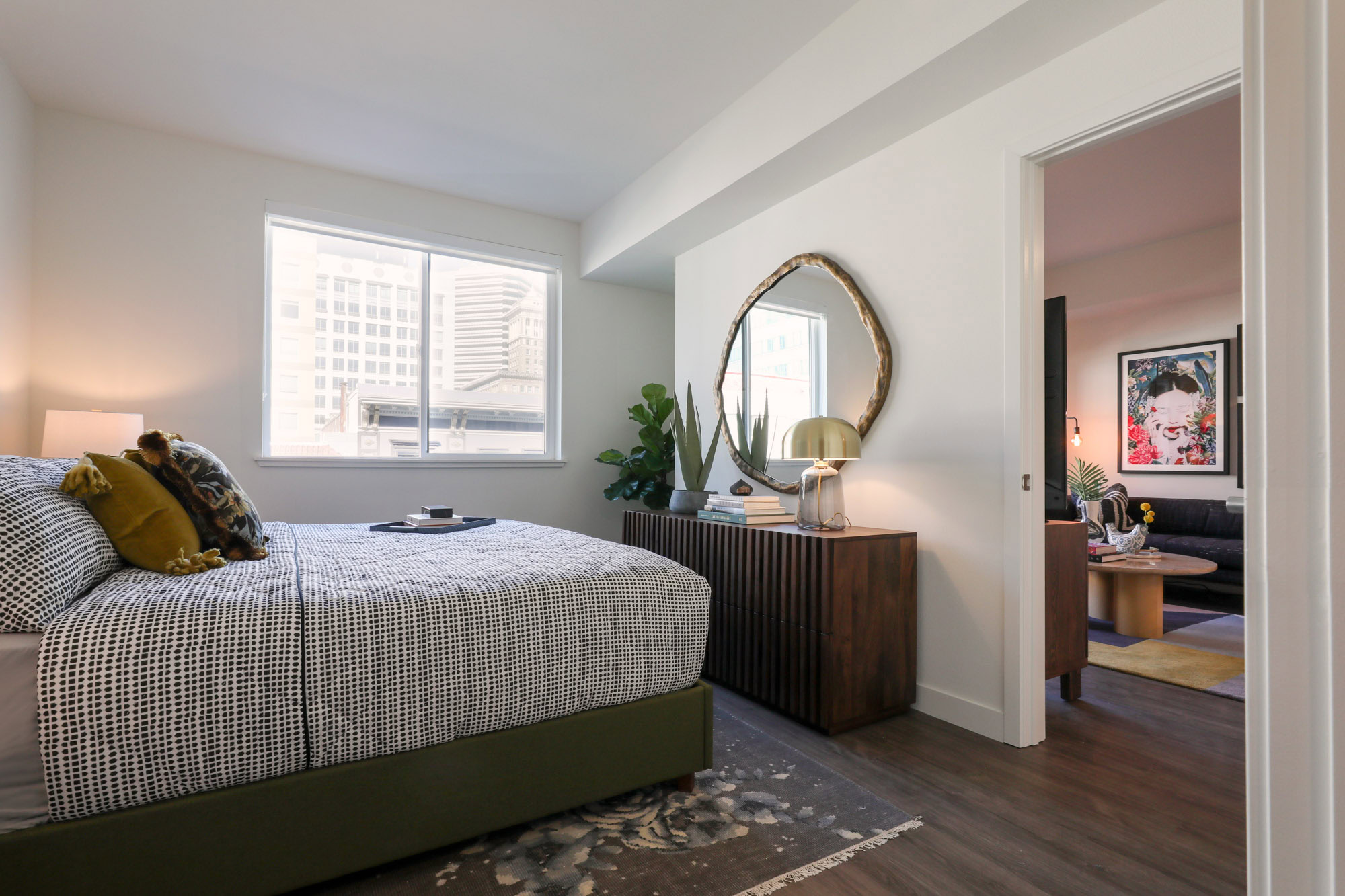 An apartment bedroom with a window and a door to the living room at the Webster Eleven downtown Oakland apartments for rent