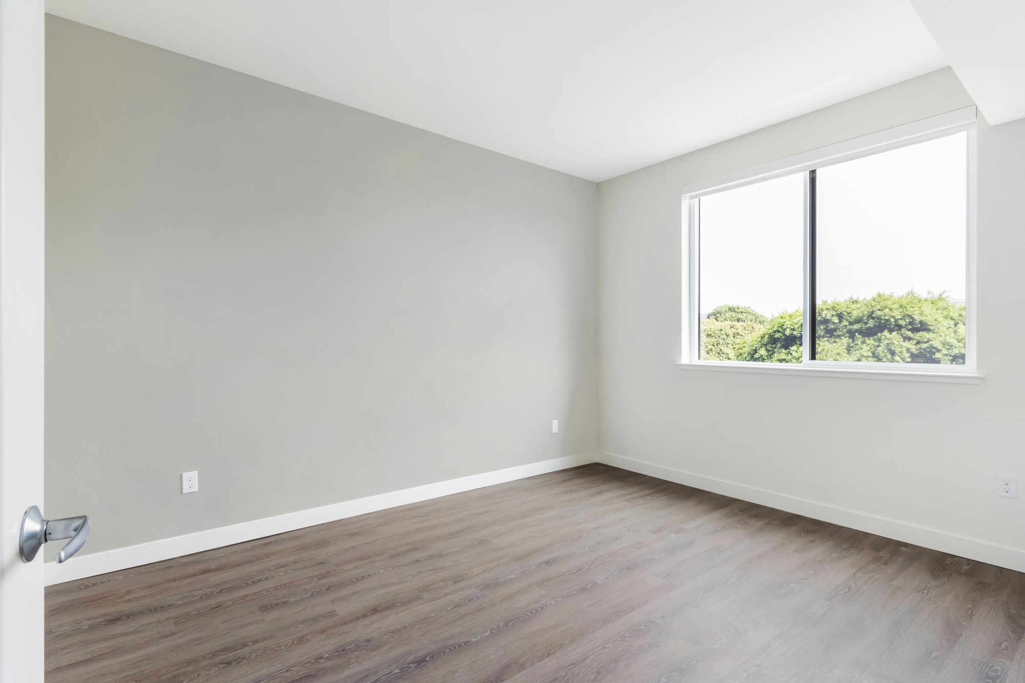 A bedroom with hardwood floors and windows at the Webster Eleven downtown Oakland apartments for rent