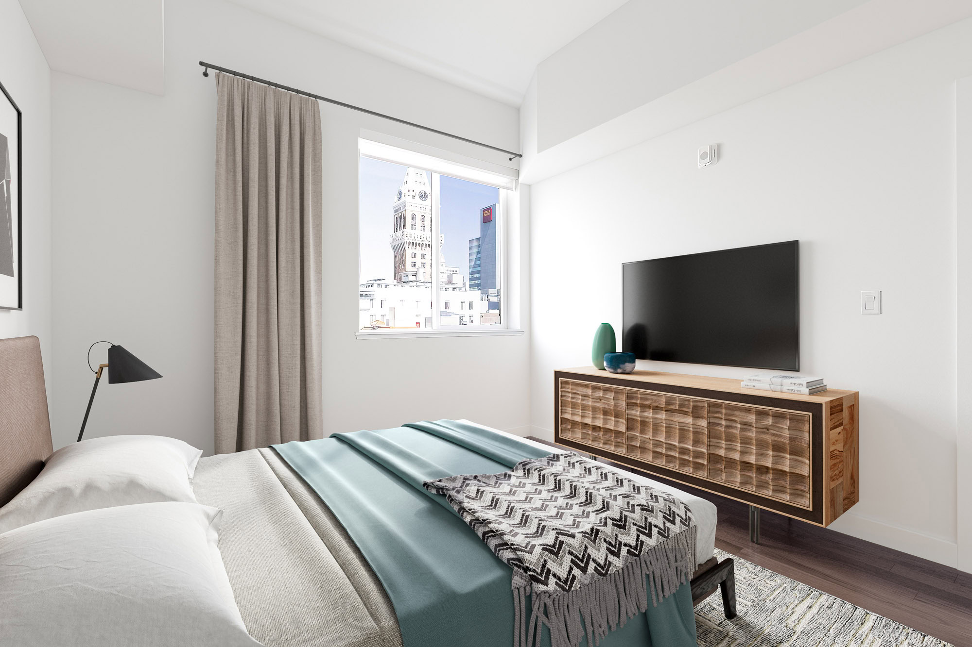 A bedroom with hardwood floors and a window overlooking the city skyline at the Webster Eleven apartments in downtown Oakland