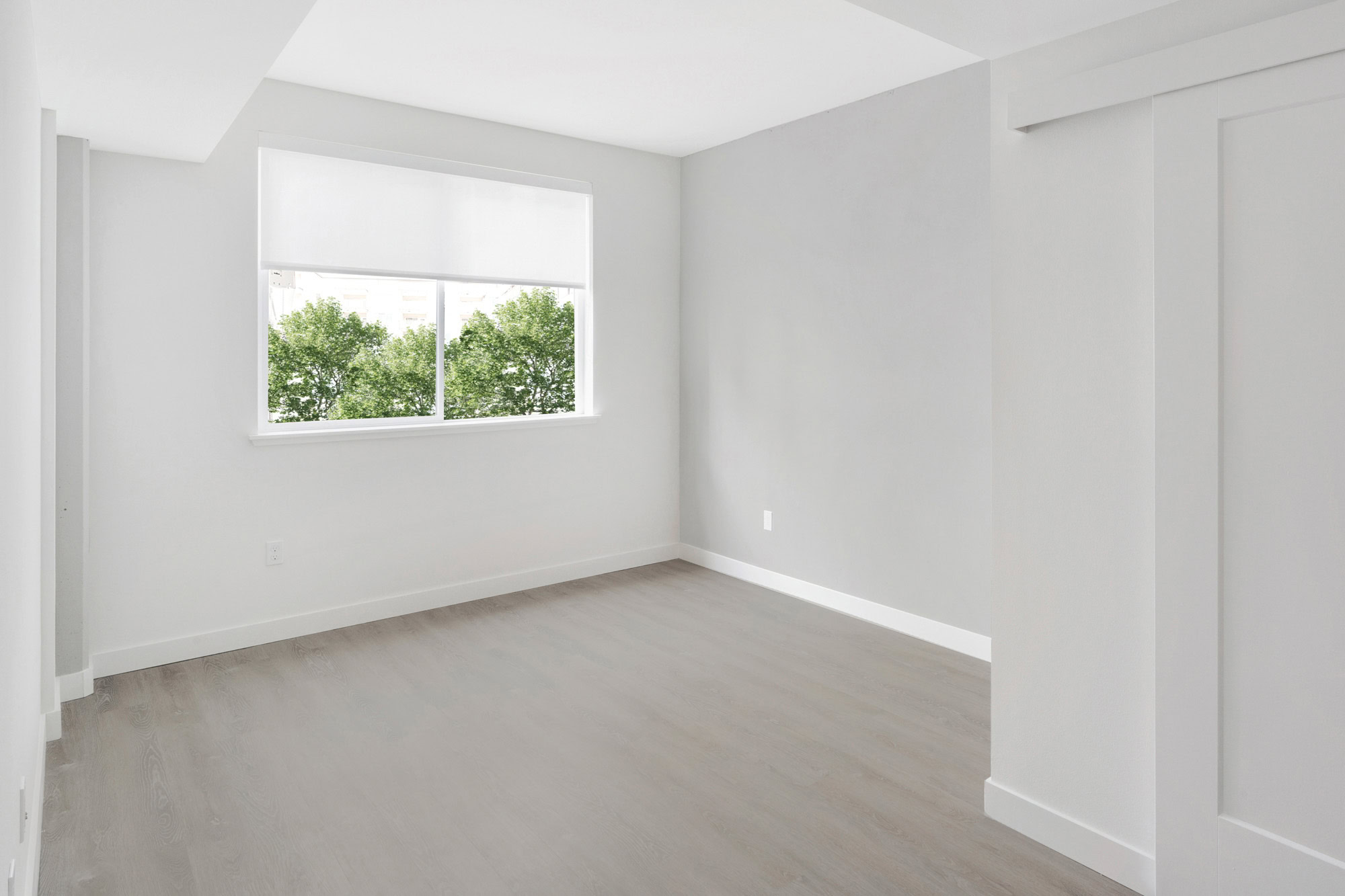 A bedroom with hardwood floors and a window at the Webster Eleven apartments for rent in downtown Oakland
