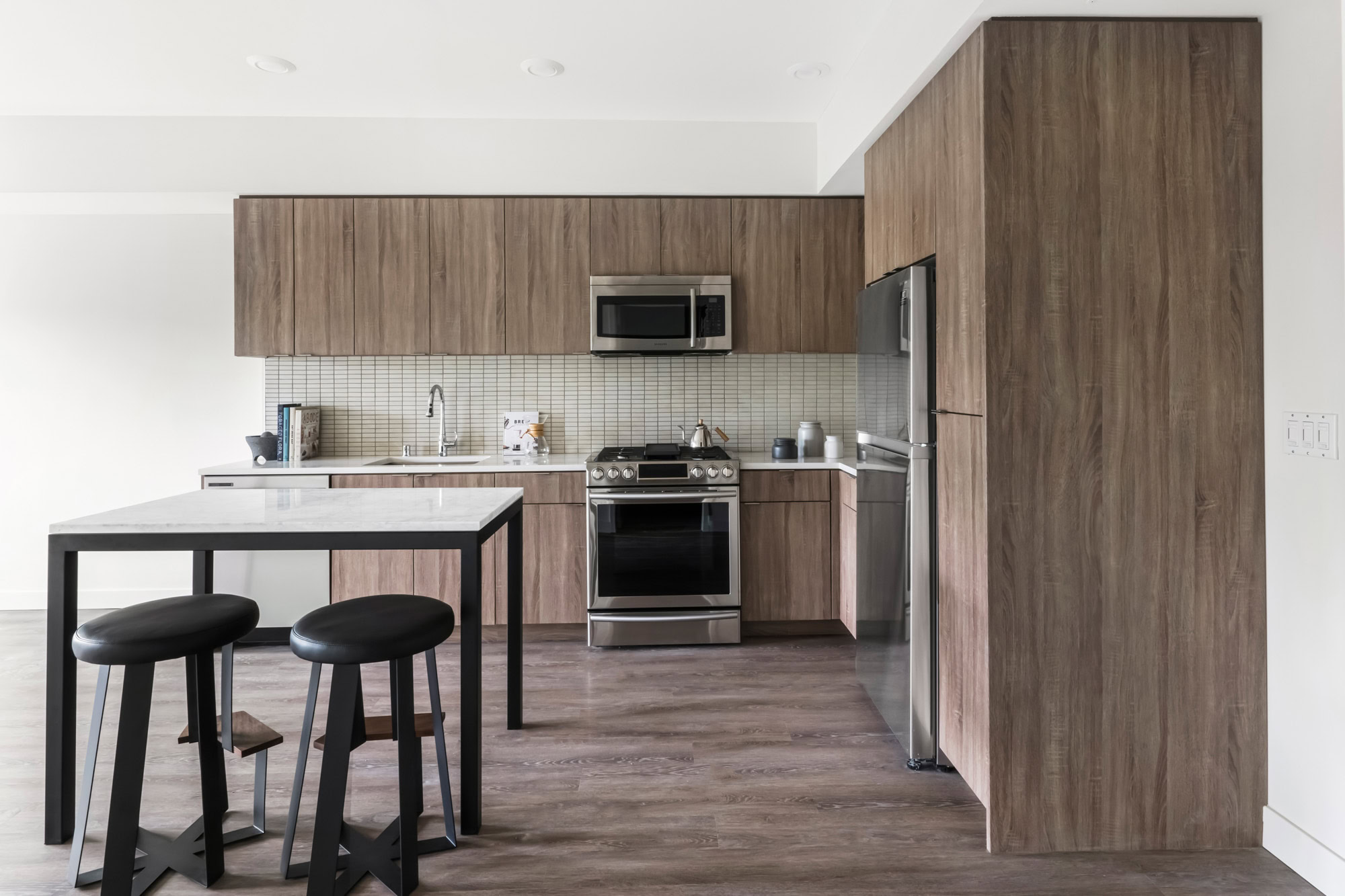 An open plan kitchen with a kitchen island with hardwood floors at the Webster Eleven downtown Oakland apartments for rent