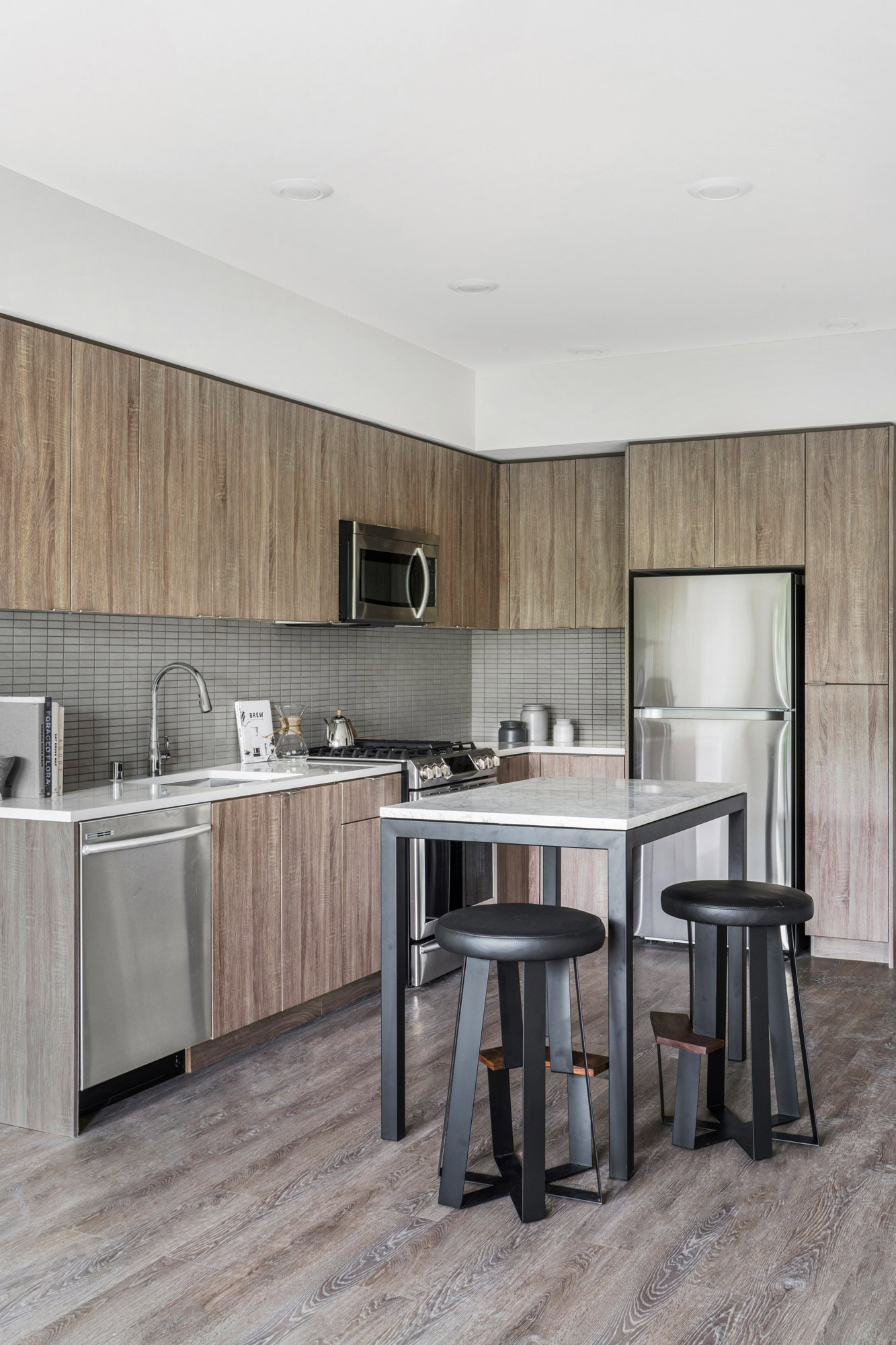 An open plan kitchen with a kitchen island with hardwood floors at the Webster Eleven downtown Oakland apartments for rent