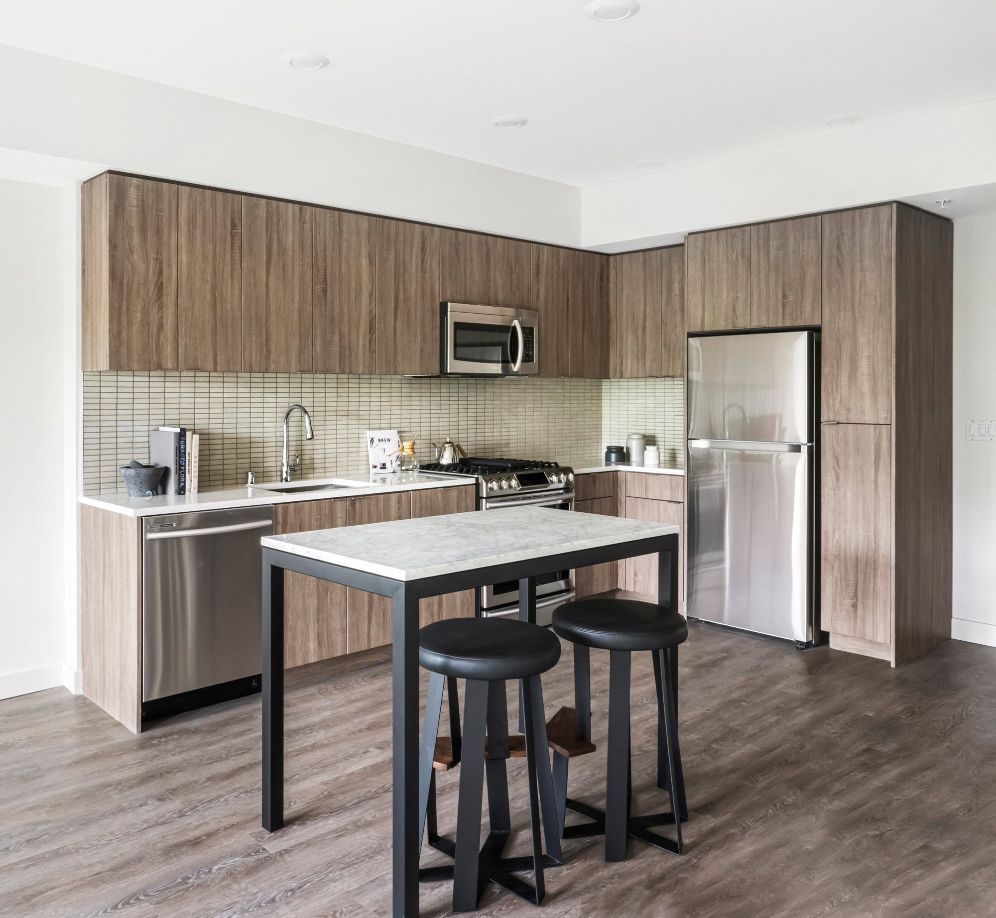 An open plan kitchen with a kitchen island with hardwood floors at the Webster Eleven downtown Oakland apartments for rent