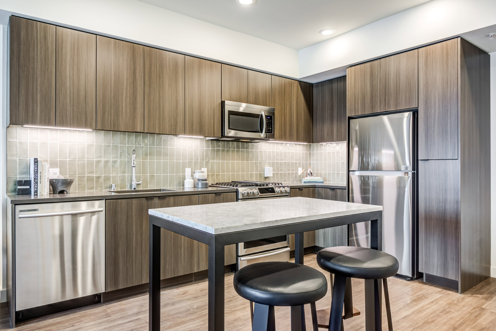 An open plan kitchen with a kitchen island with hardwood floors at the Webster Eleven downtown Oakland apartments for rent