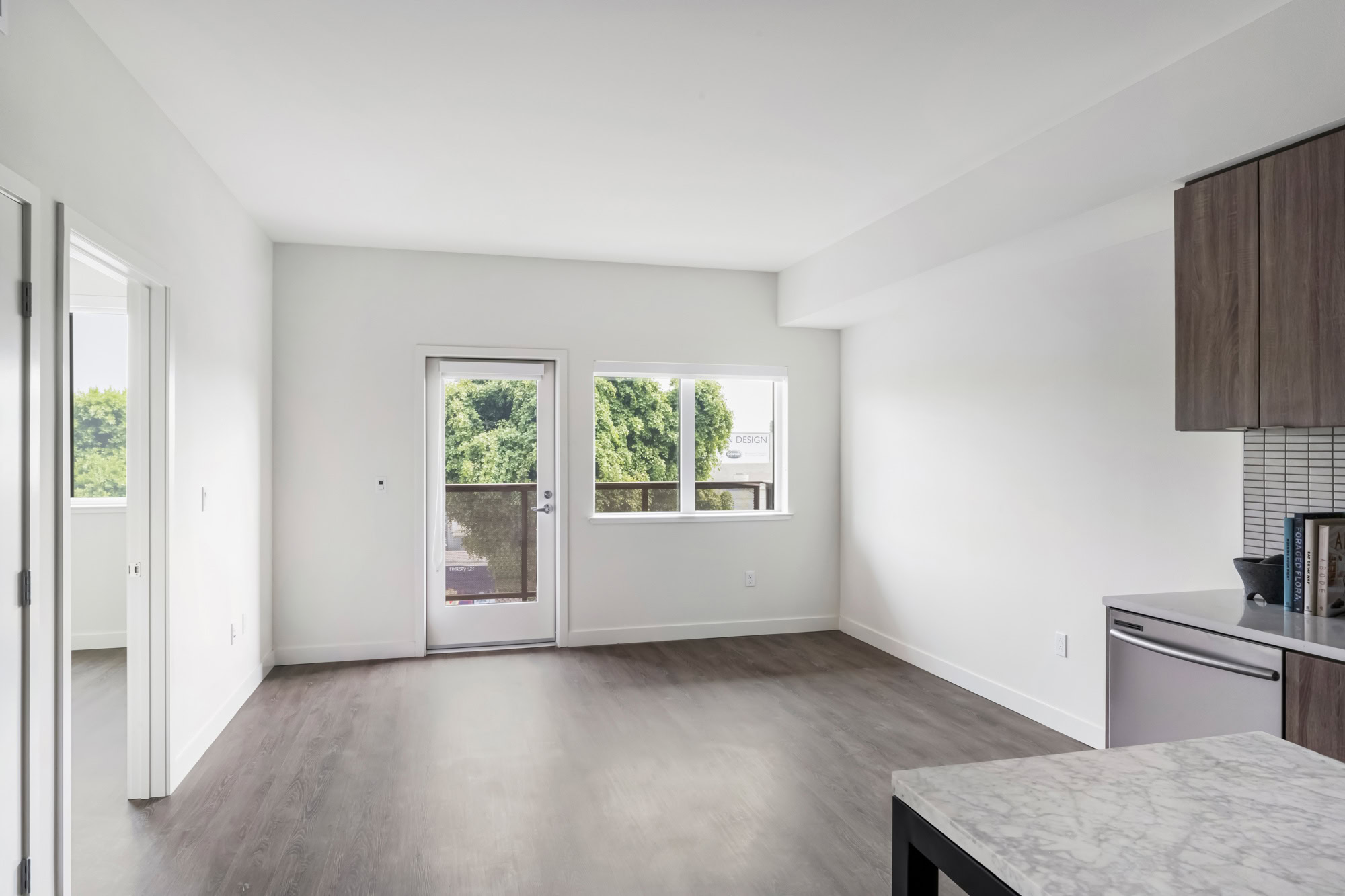 An open plan apartment living room with hardwood floors and a balcony door at the Webster Eleven apartments in downtown Oakland