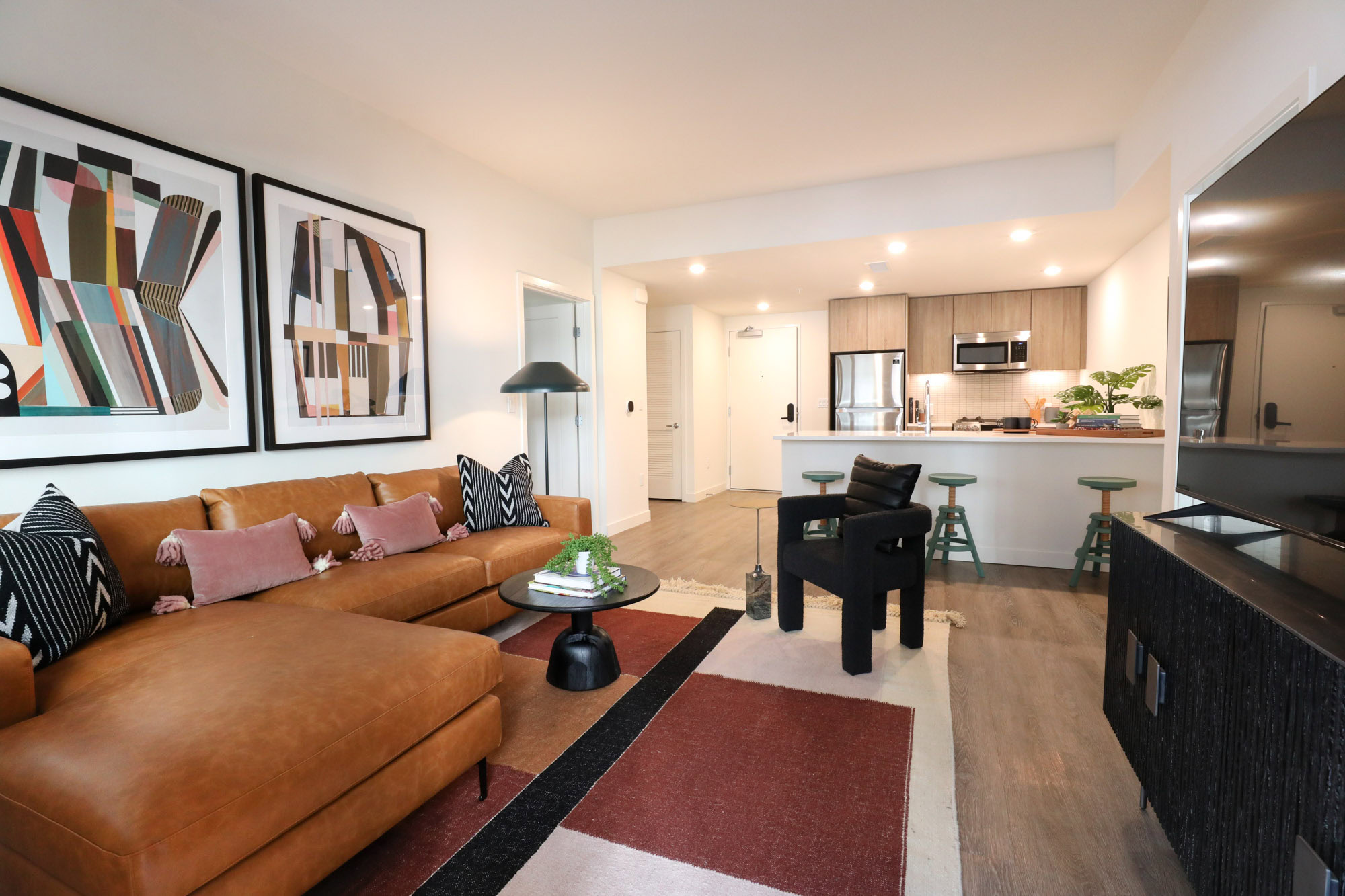 An open plan living room with hardwood floors leading to a peninsula and kitchen at the Webster Eleven in downtown Oakland