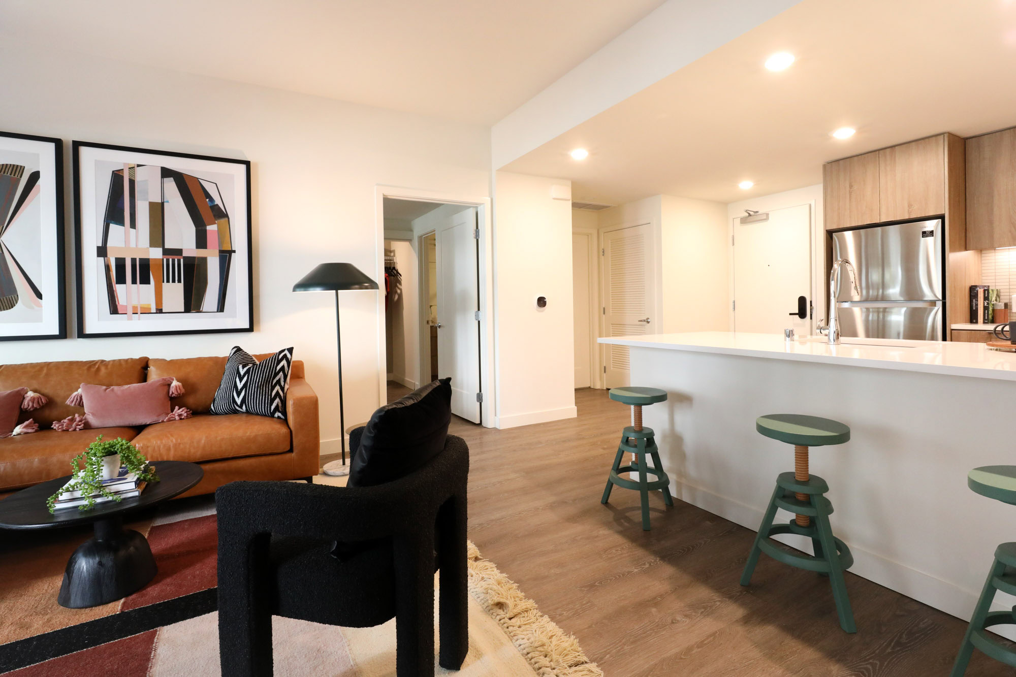 A living area with a door to a bedroom and a kitchen peninsula at the Webster Eleven apartments in downtown Oakland