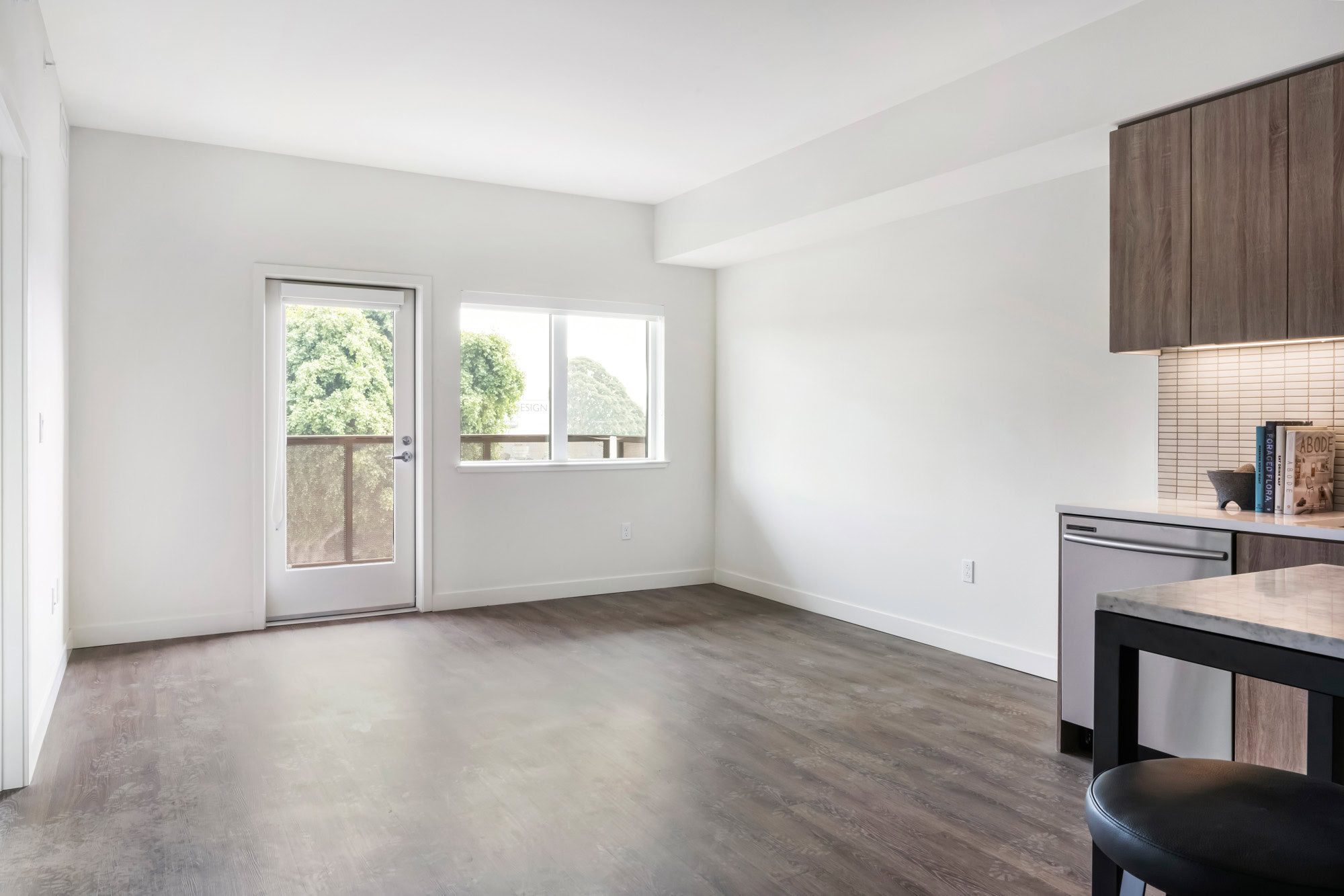 An open plan living room with a door to the balcony at a Webster Eleven apartment in downtown Oakland