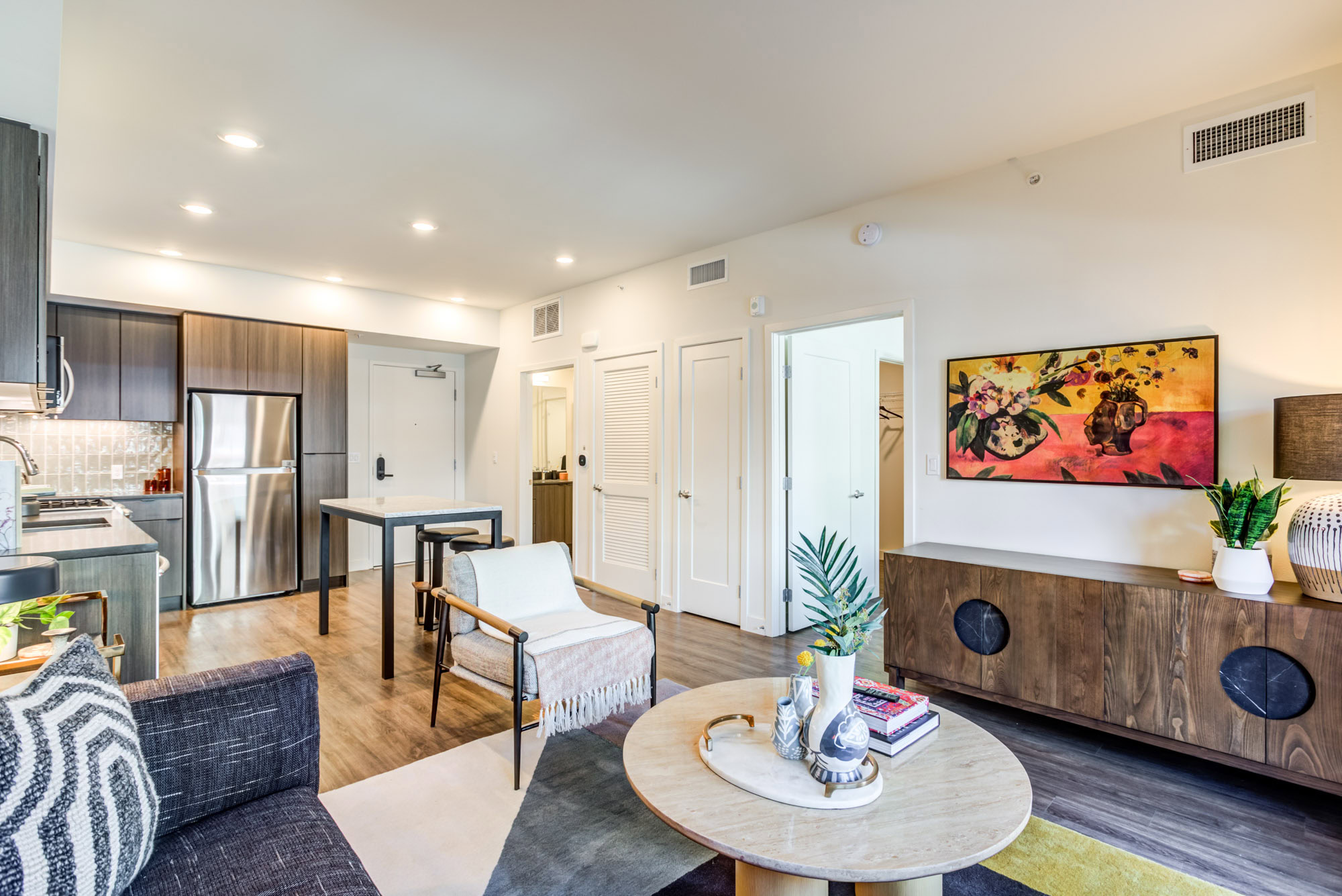 A living room with hardwood floors and open kitchen with an island at the Webster Eleven apartments in downtown Oakland